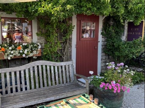 A cabin with a brown door covered in vines on a sunny day.