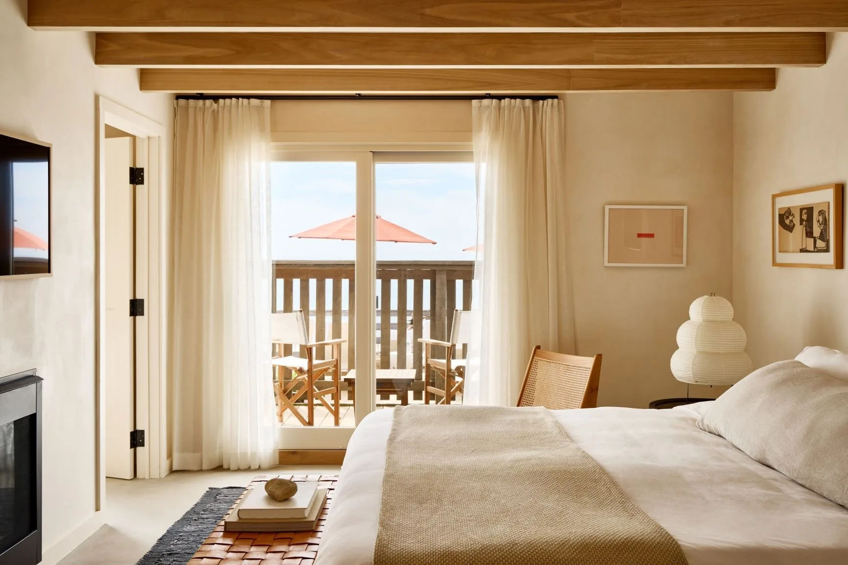 Cozy room at Marram Montauk, with a private balcony and loungers under an umbrella, plus natural hues and materials in the room decor
