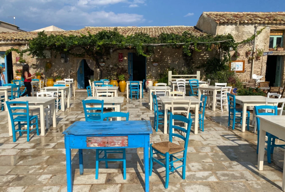 A pretty outdoor restaurant with blue and white tables in a couryard.