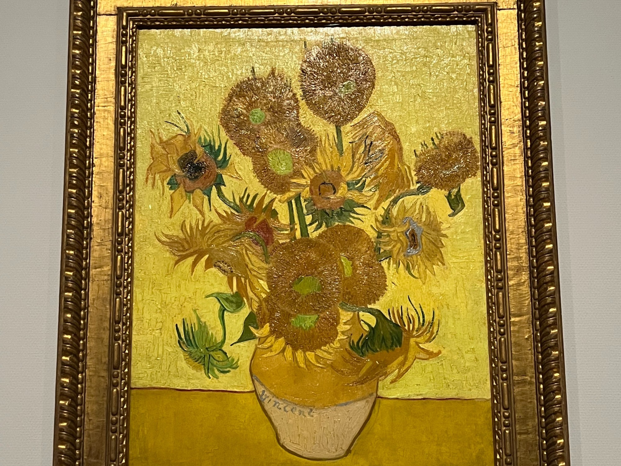 A framed painting of flowers in a vase hung on a wall