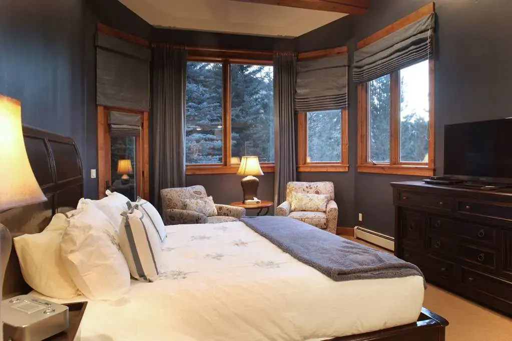 A king bedroom with vintage furniture and wrap-around view of the pine forests