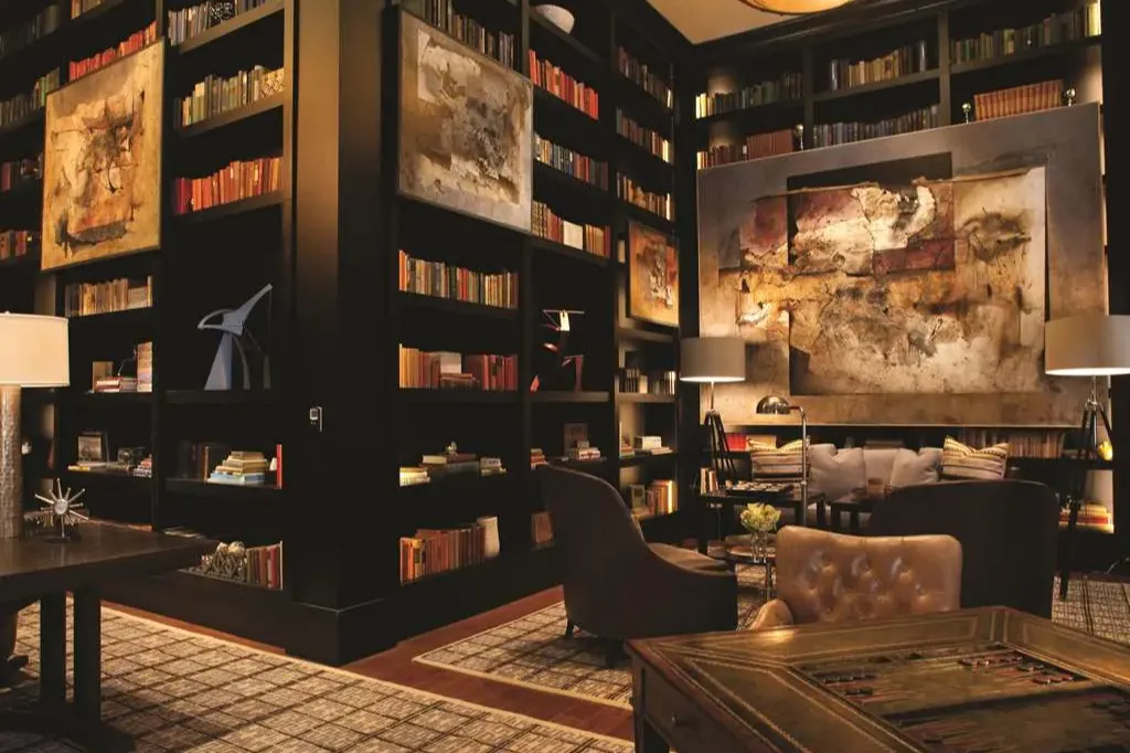 Moody library-slash-common space at The Sebastian - Vail with books lining sleek shelves and comfy but classy furniture throughout