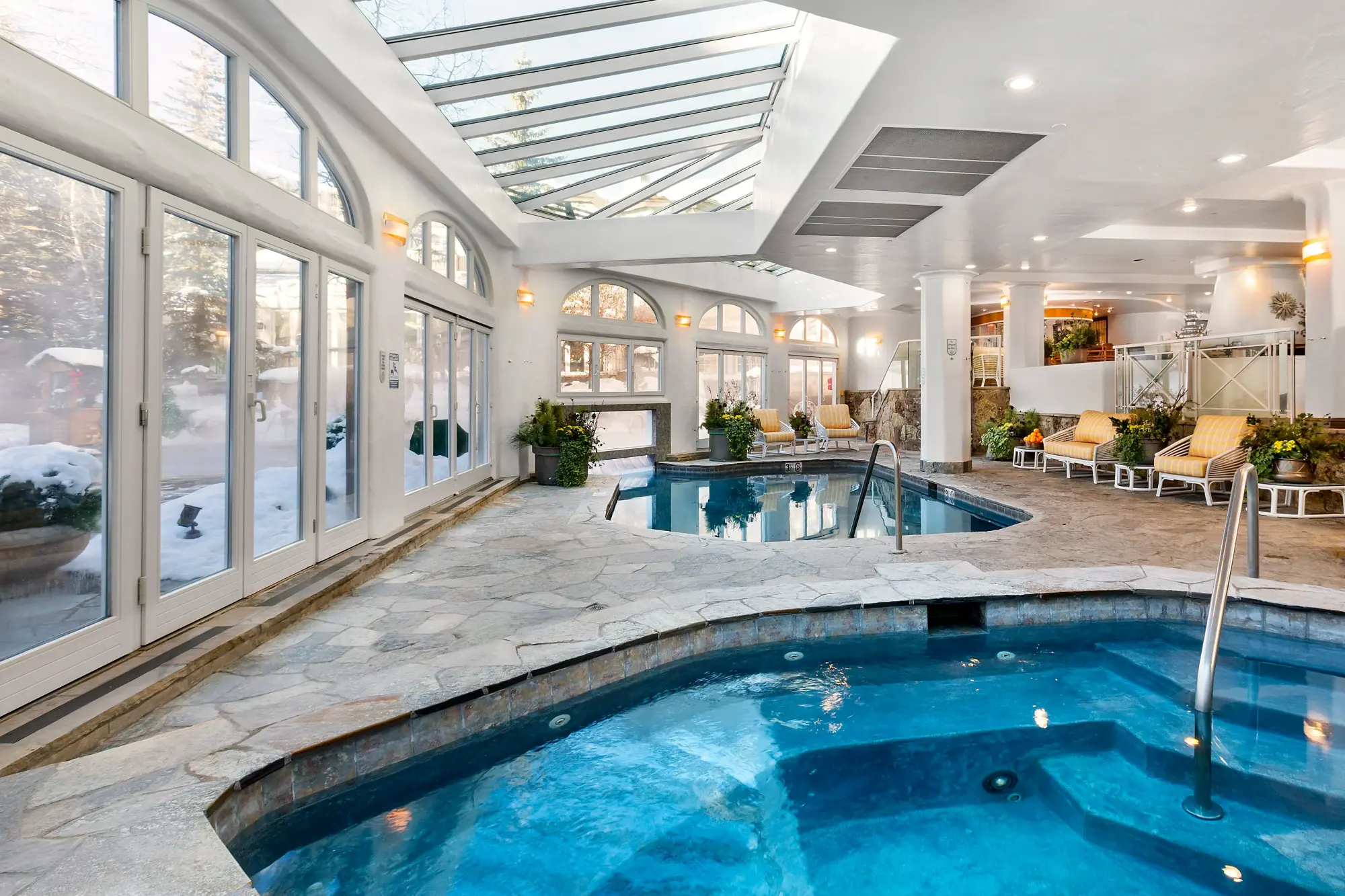 An inside peak at Sonnenalp Hotel's classy indoor pool area, with huge glass windows, doors and skylights letting in plenty of natural light and revealing blizzard-like conditions outside