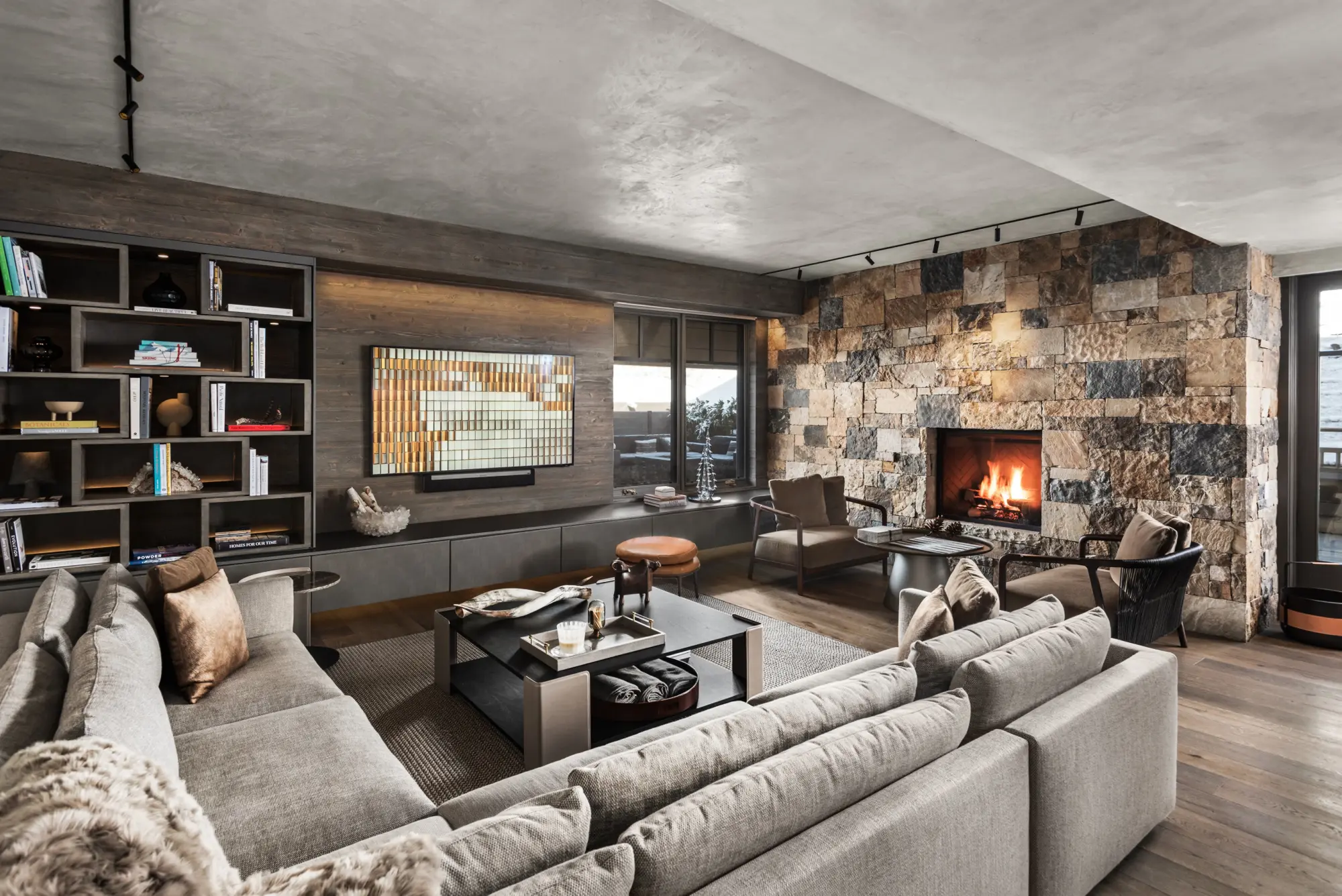 Chic, contemporary common space with plenty of comfy seating and a small fireplace within a stone-brick wall
