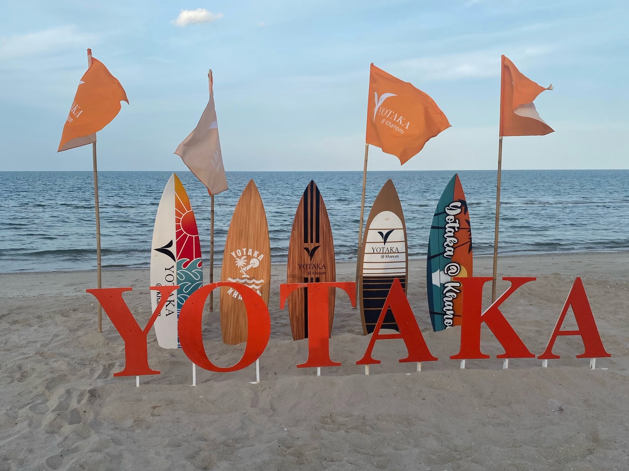 A sign on the beach with surfboards during the daytime.