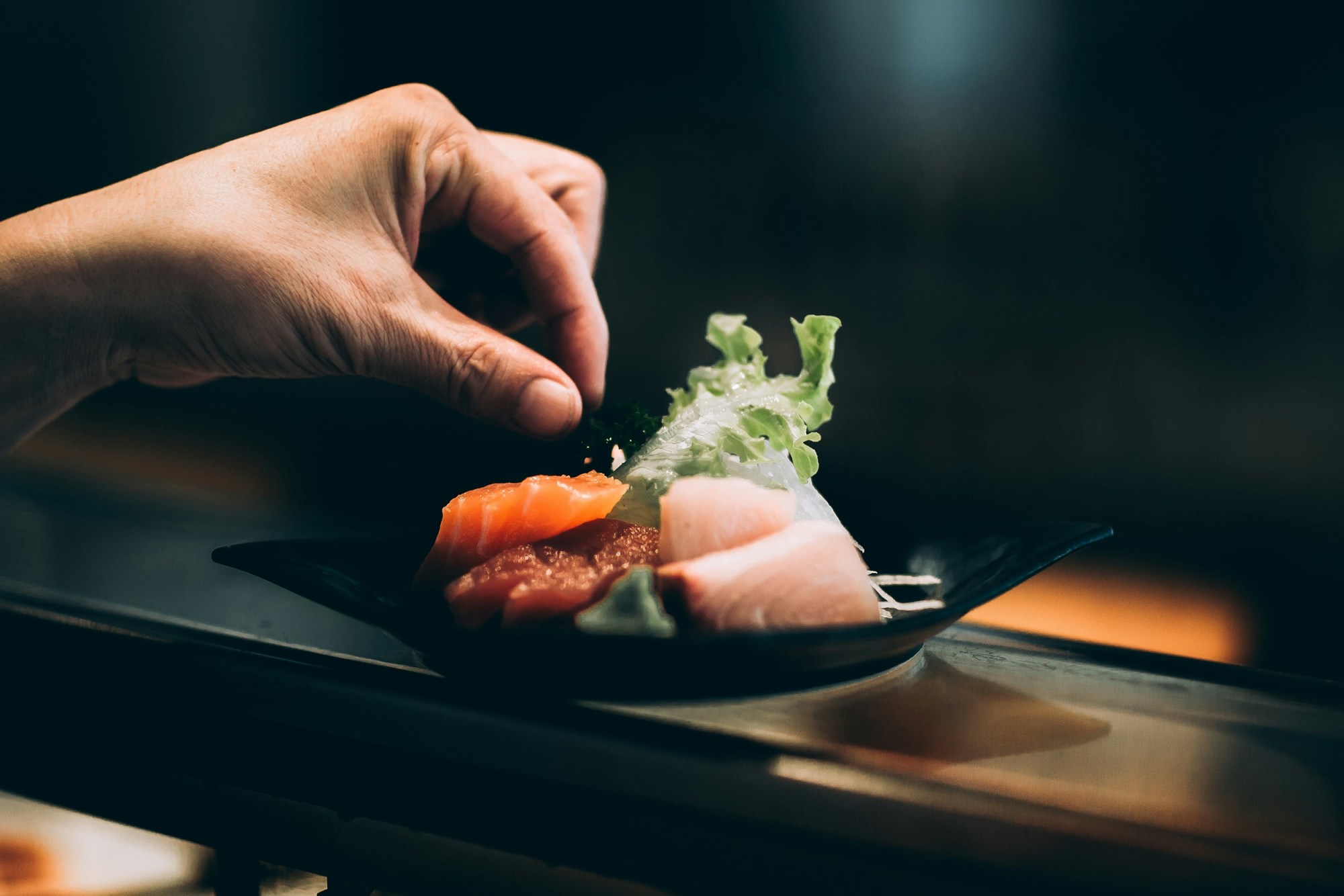 A black plate with carefully arranged sashimi.