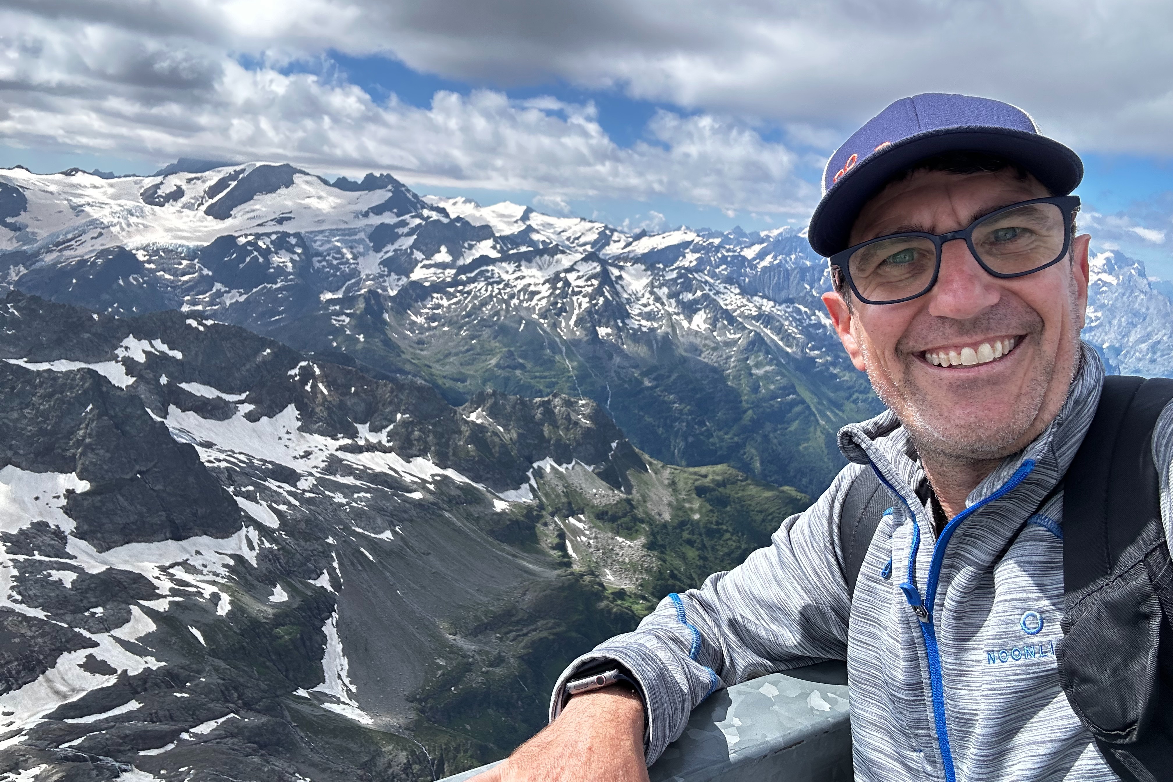 Advisor taking a selfie with snow-capped mountain peaks behind him.