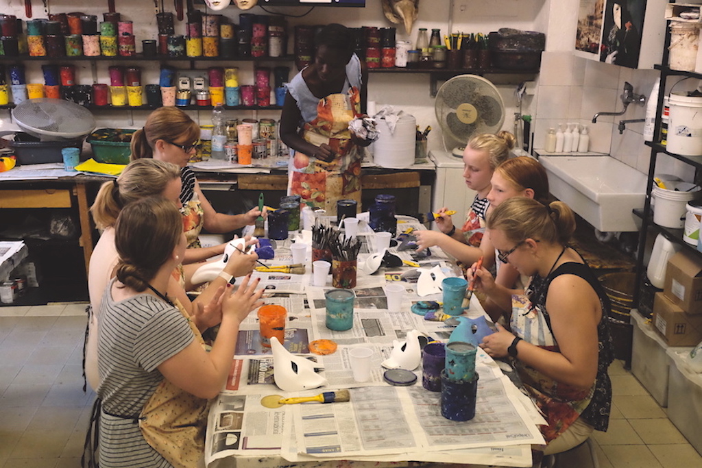 A group of kids sit around a craft table decorating masks.