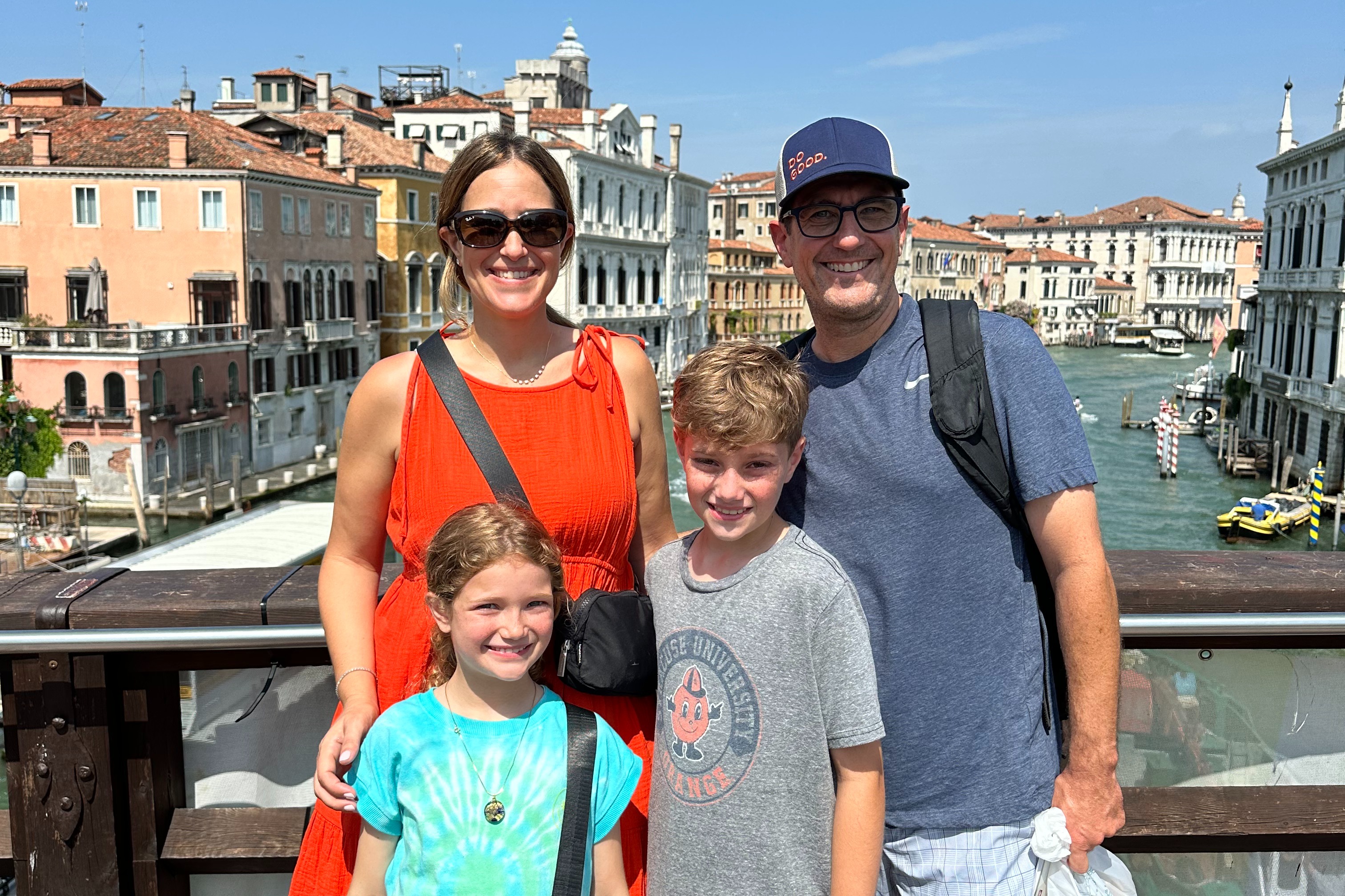 Two adults and two children standing on a bridge with a canal behind them.