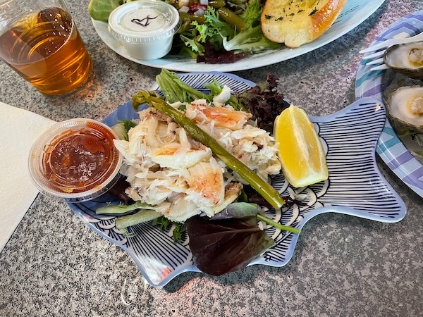 A vibrant seafood salad with a side of sauce and a refreshing drink, perfect for a delightful meal.