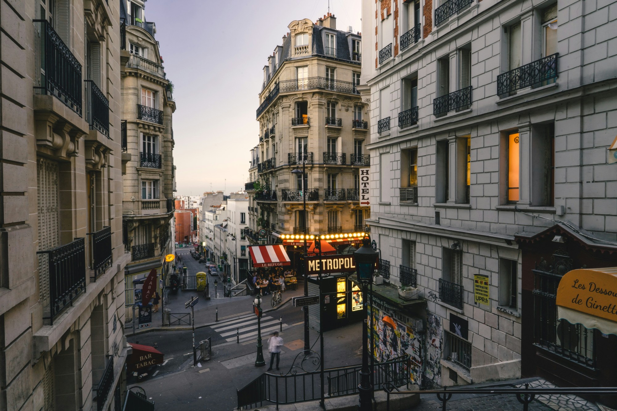 City streets with buildings and people at dusk.