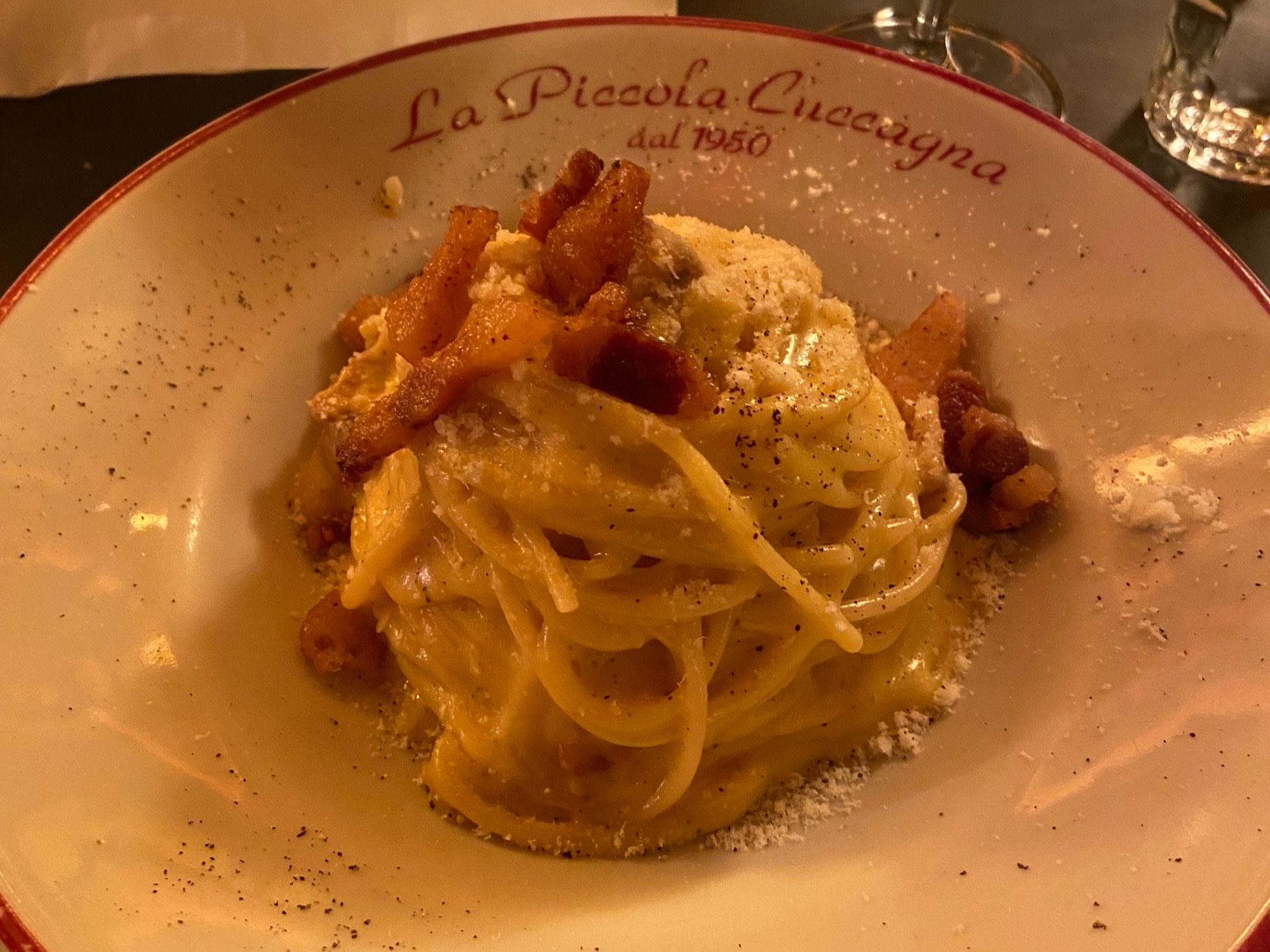 Authentic pasta carbonara artfully arranged in a dish and covered with Parmasean.