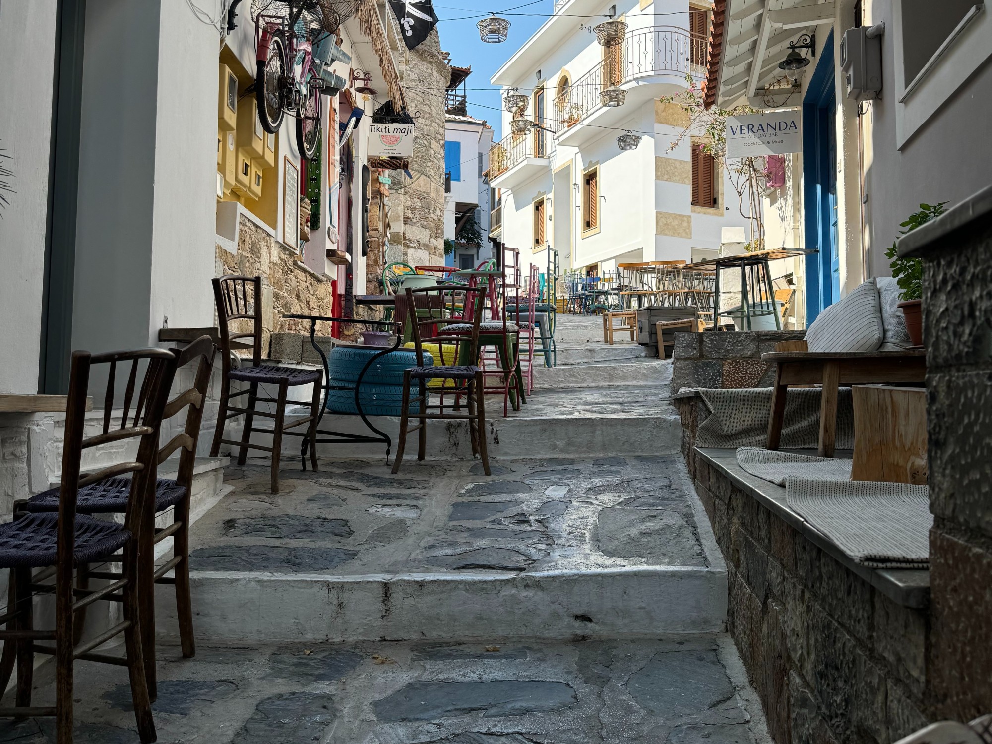 Street in town with shops, tables and chairs.
