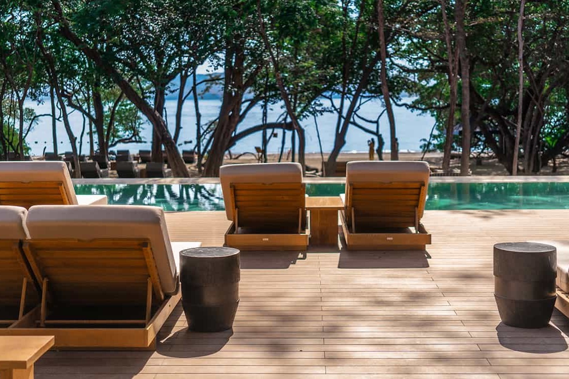 Casa De Playa's pool with ocean view faces the waves on a sunny day.