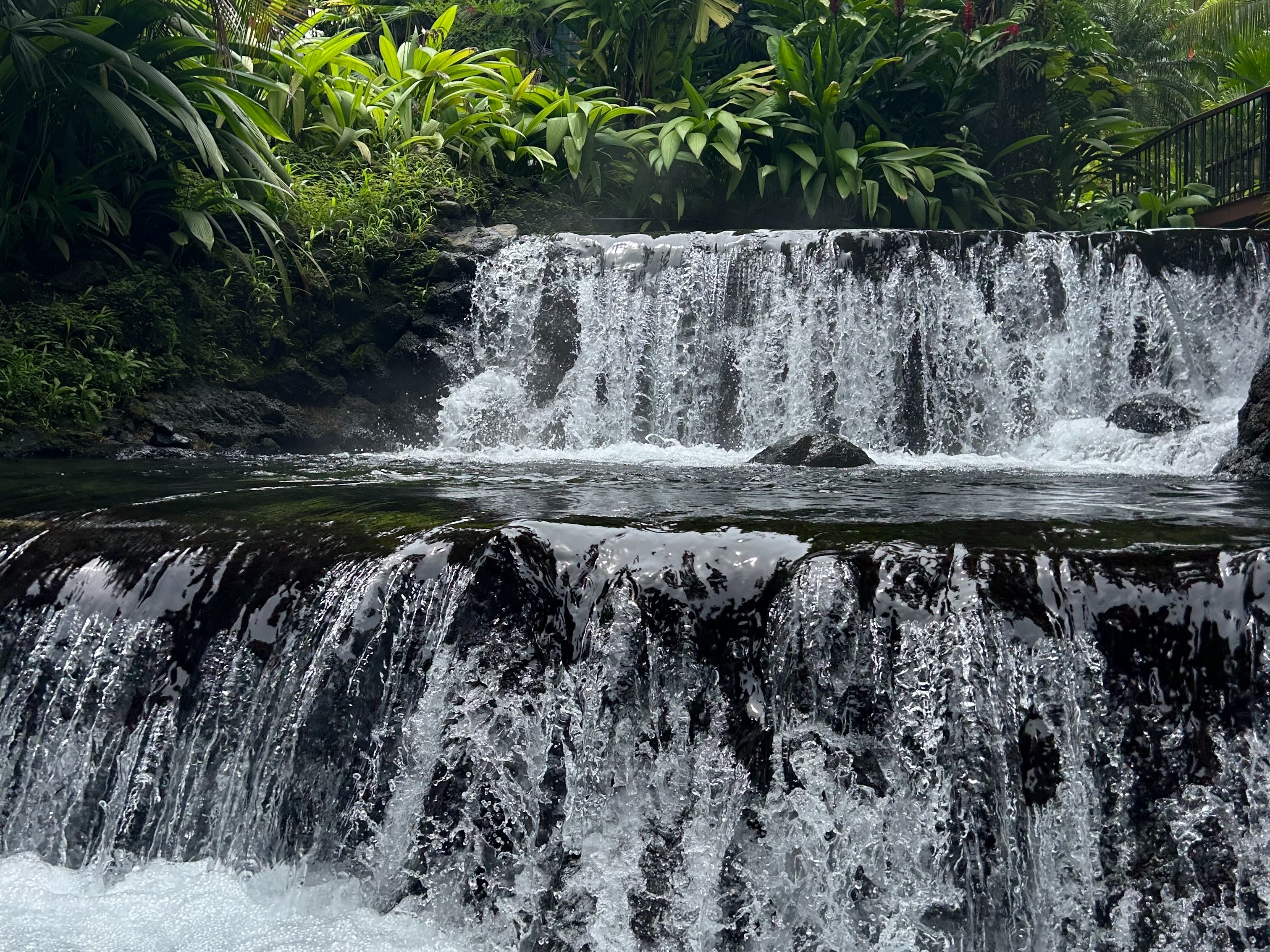 A multi-tiered waterfall surrounded by lush greenery.