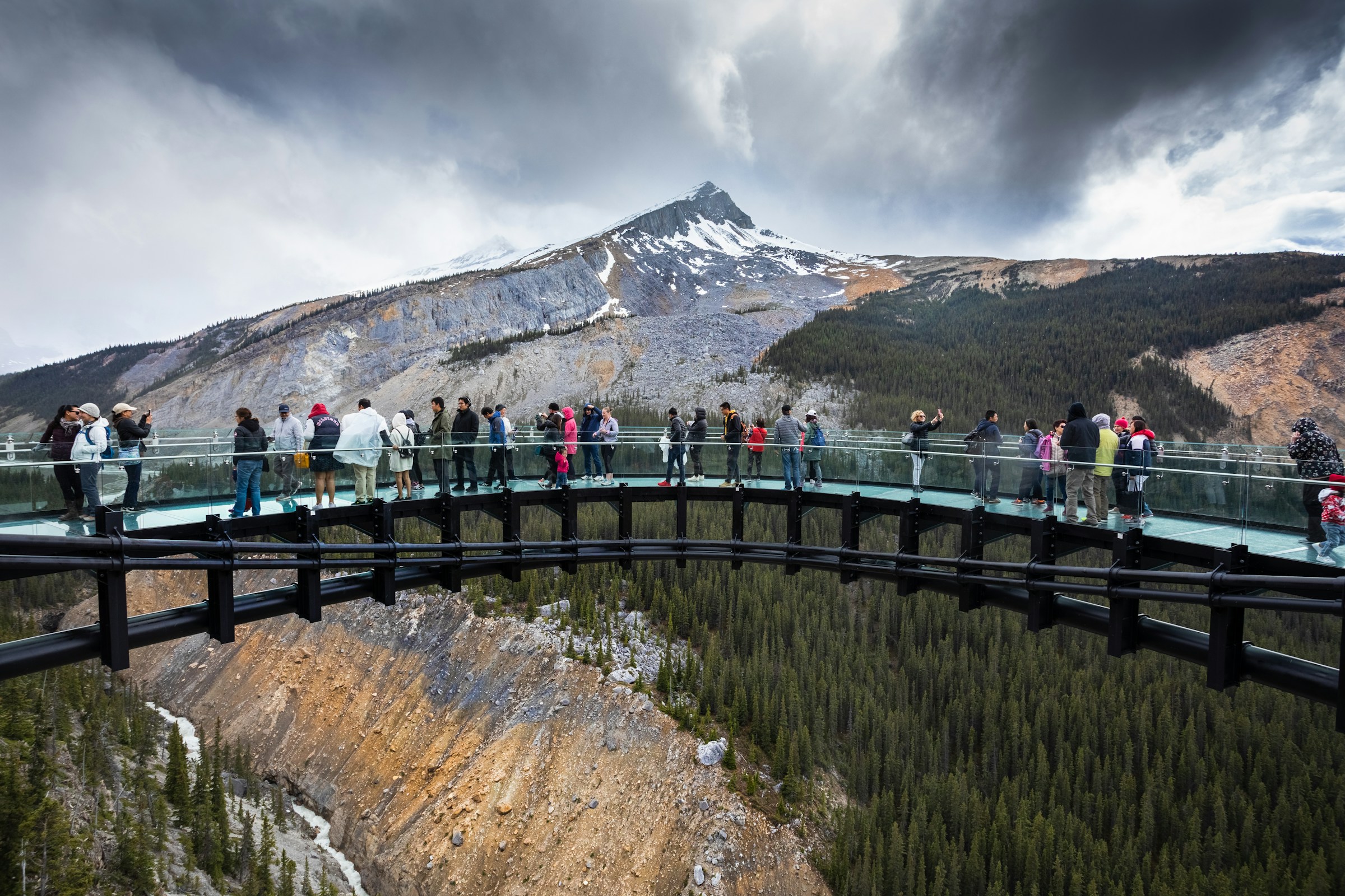 People at the glass-floored Skywalk at Columbia Icefield on a cloudy day.