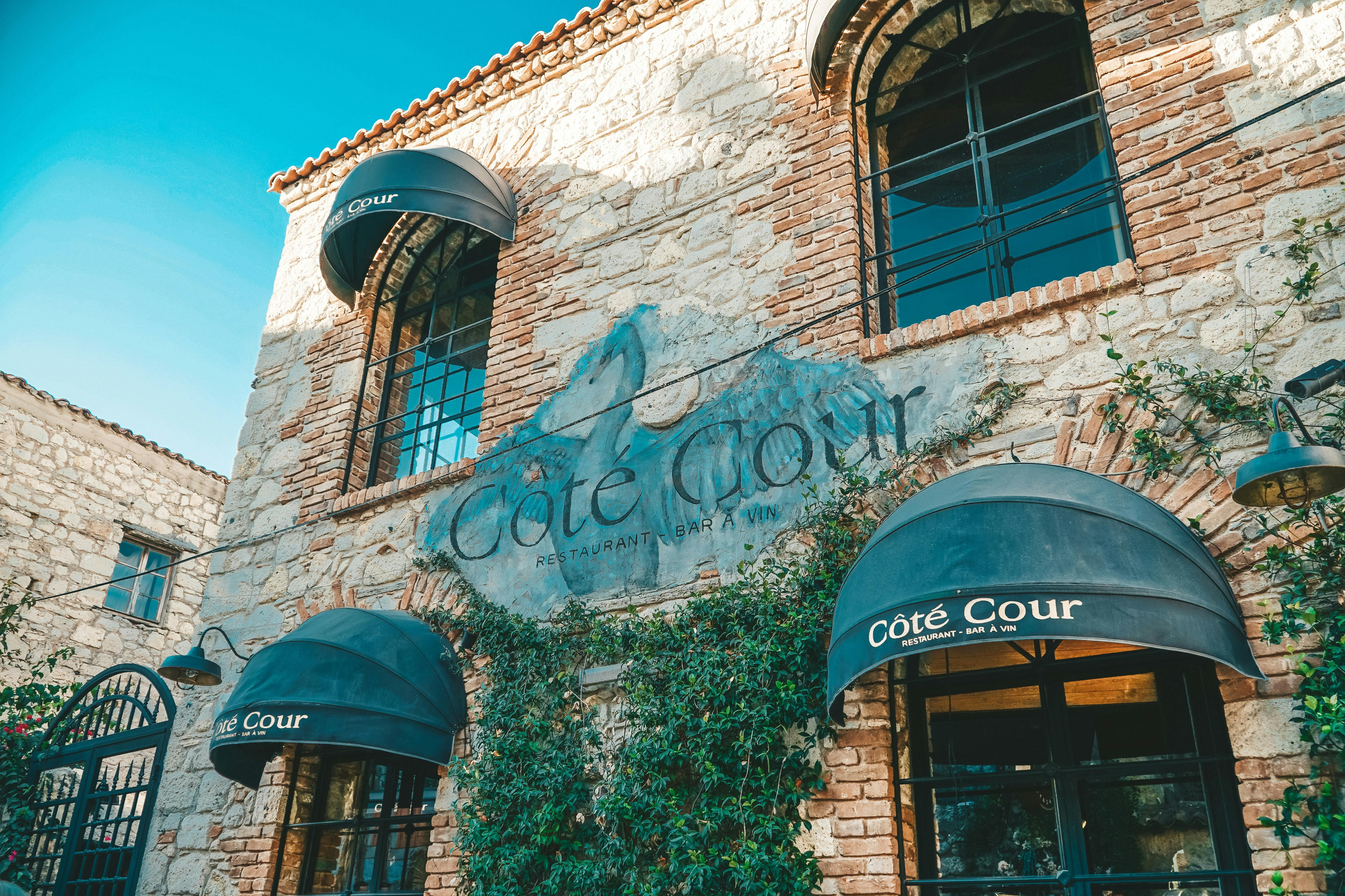 A low-angled view of a restaurant's exterior showing a brick building with a painted mural in the middle of the restaurant's name