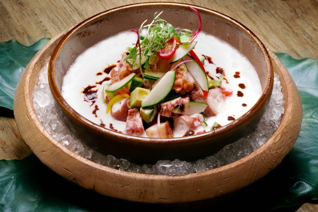 A food view of a wooden bowl with a light colored dip topped with veggies at Mamazzita.