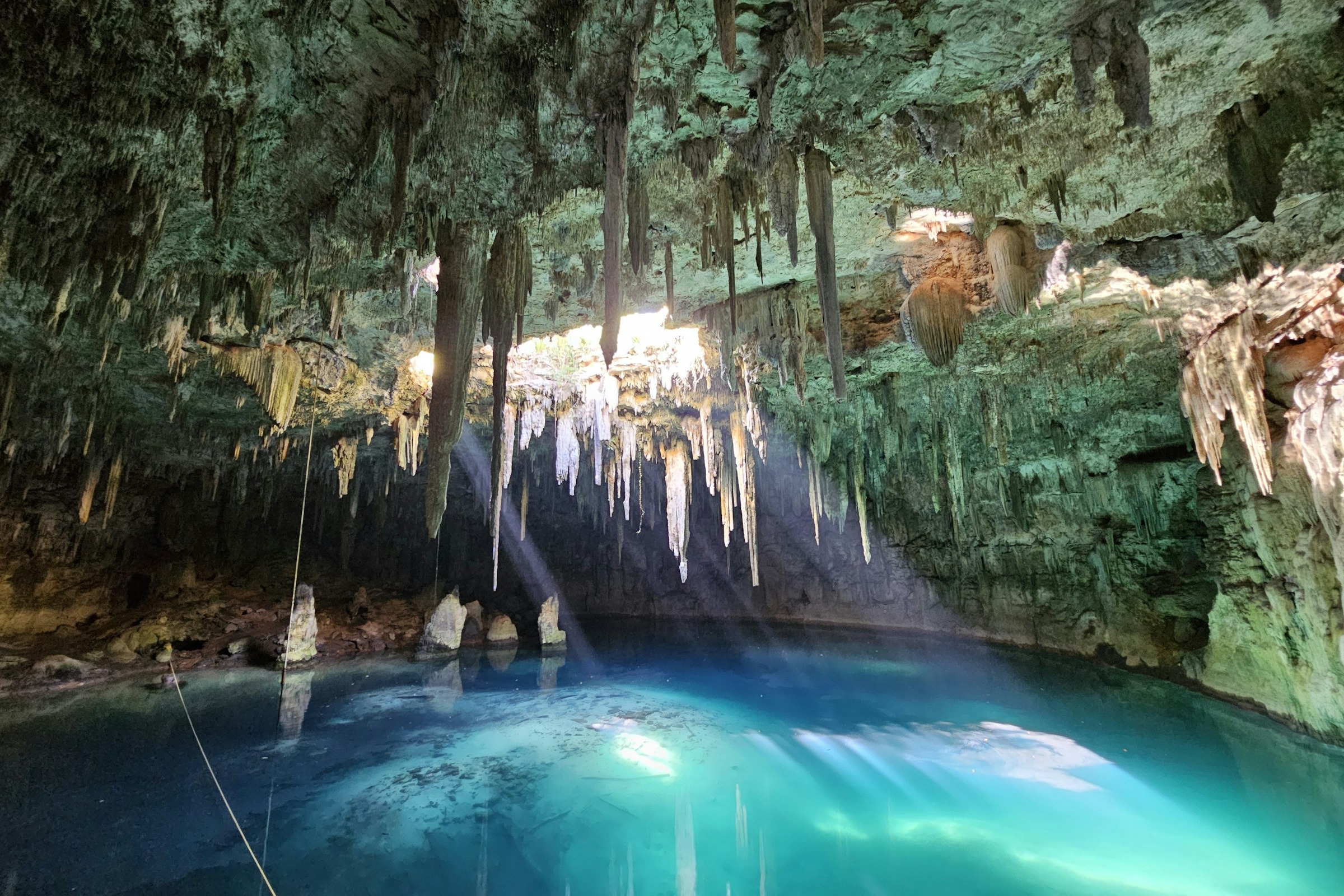 A blue pool in a cave with icicle rock formations.