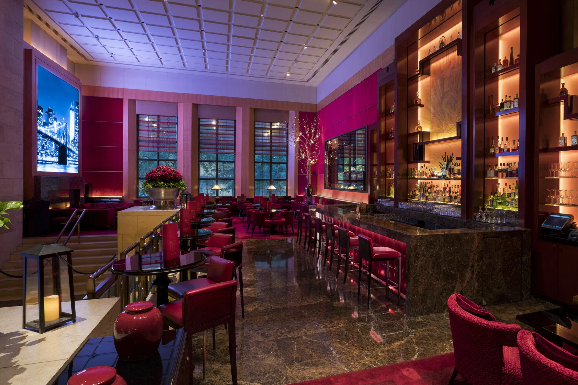 Upscale bar with lots of deep magenta accents, contemporary lighting and classy decor