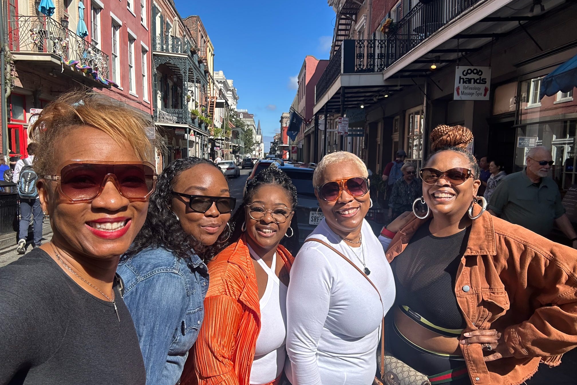 Group of women posing for a photo while standing on a city street
