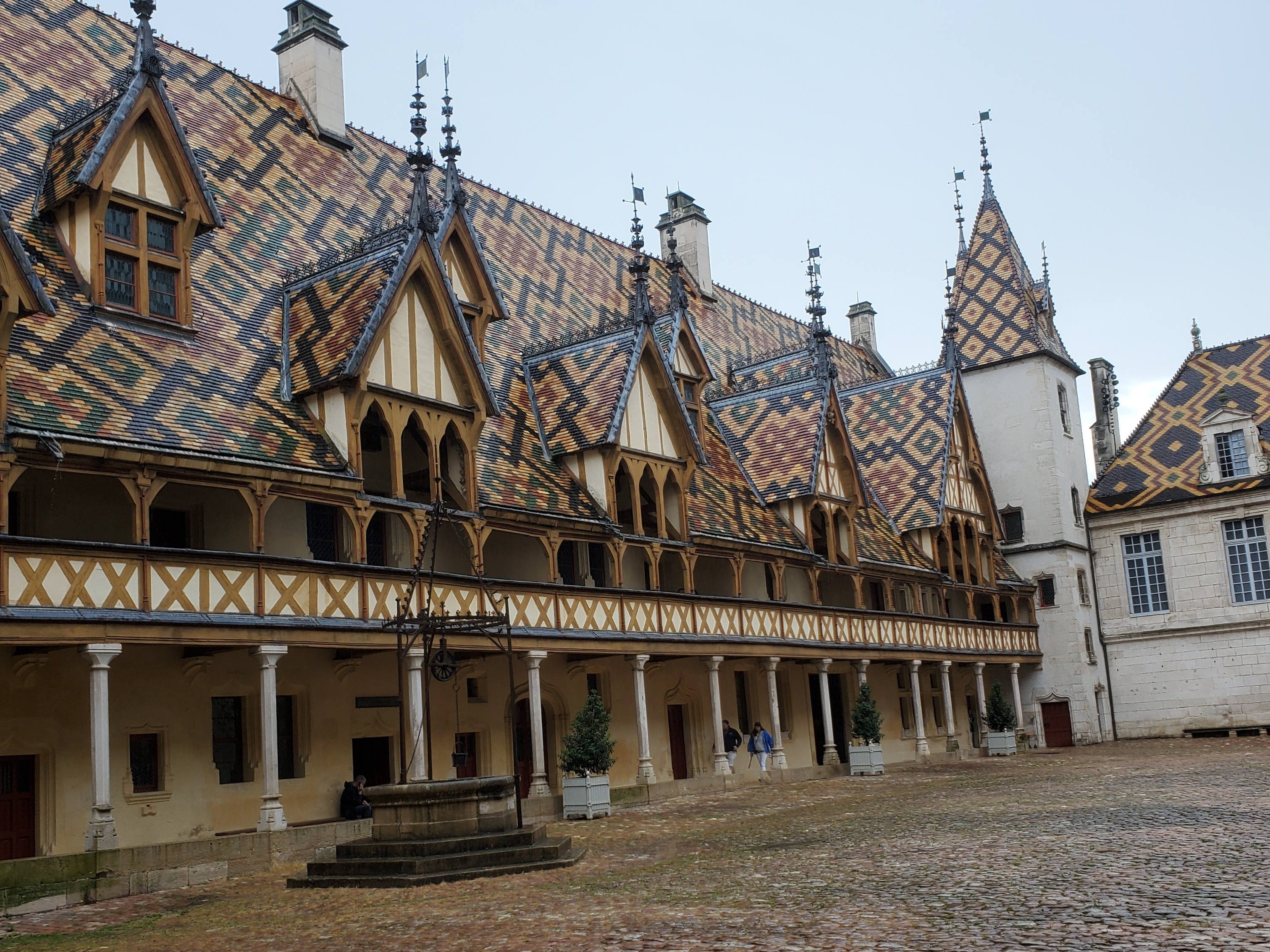 A historic building with a patterned tile roof and ornate windows in a cobblestone courtyard.