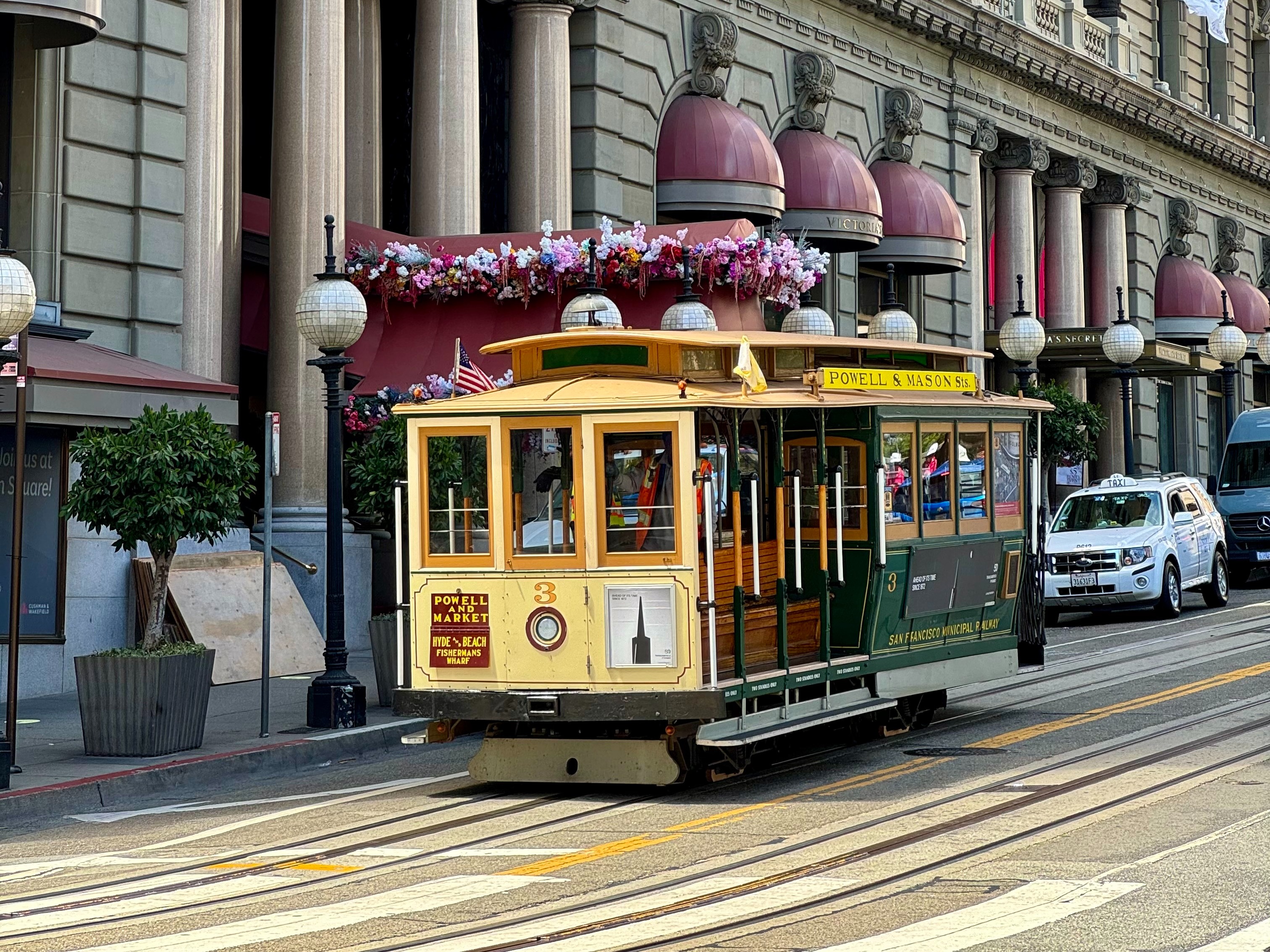 A cable car moves through the streets of San Francisco with classic architecture in the background.