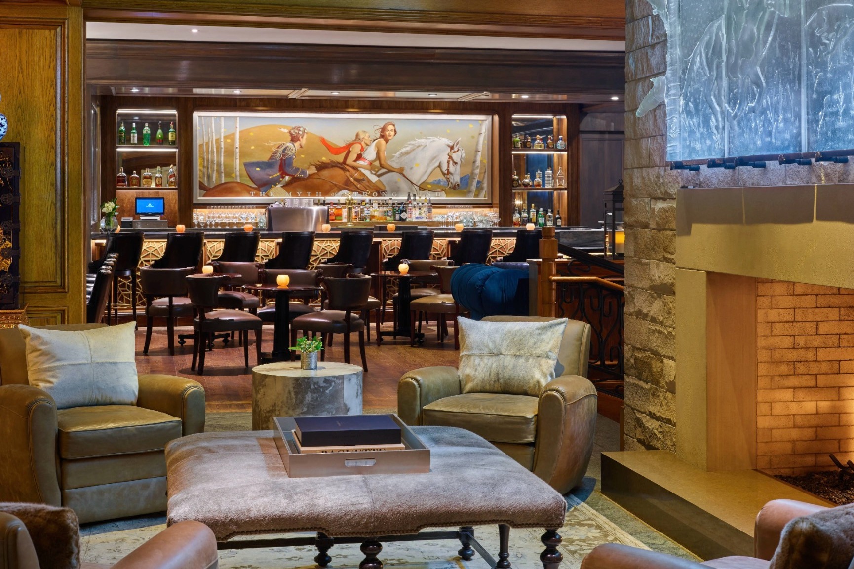 brown leather chairs in front of a fireplace with a bar behind