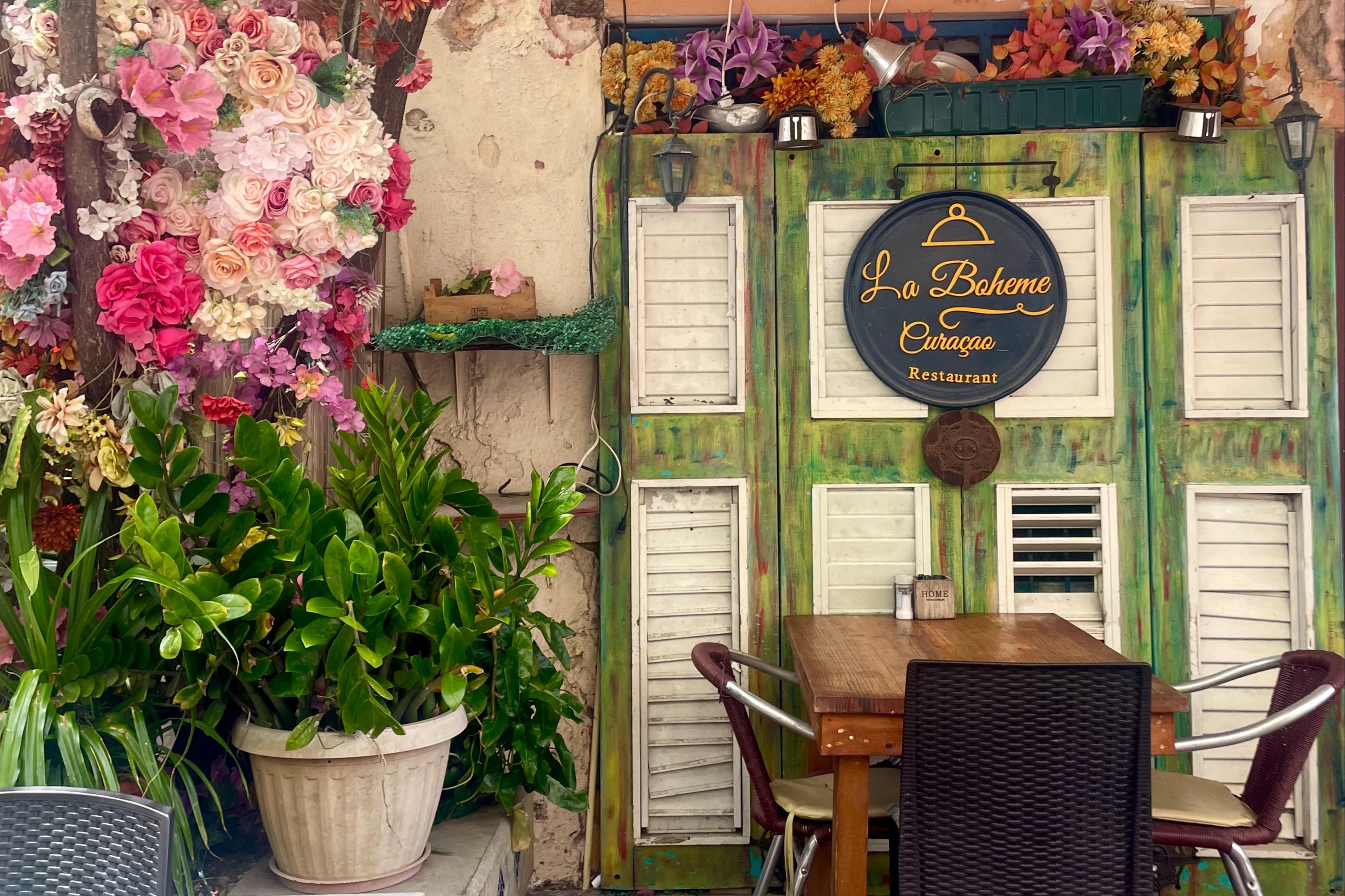 Wooden table, metal chairs and potted flowering plants.