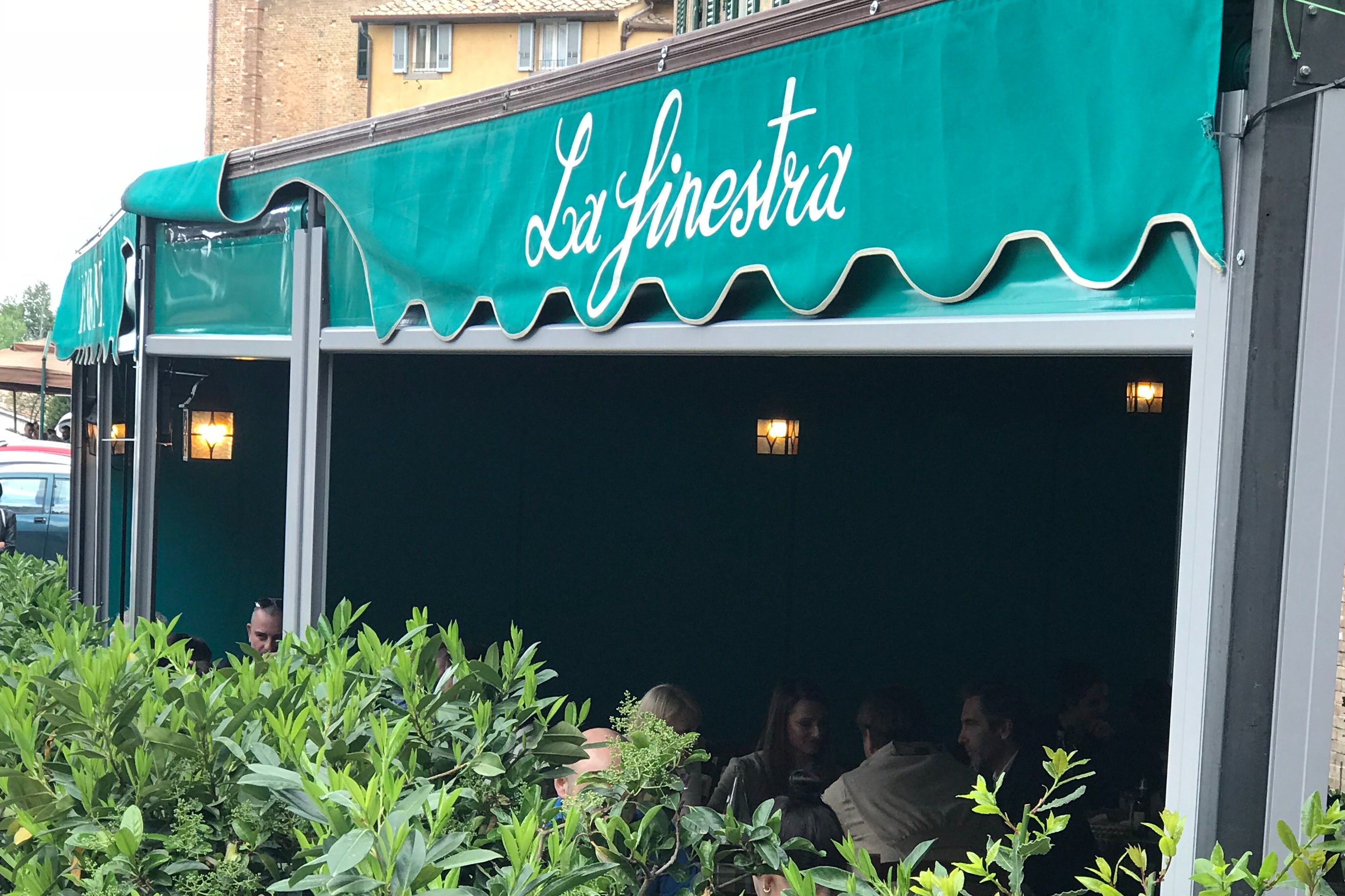Exterior of a restaurant with a green shade awning that reads "La Finestra."
