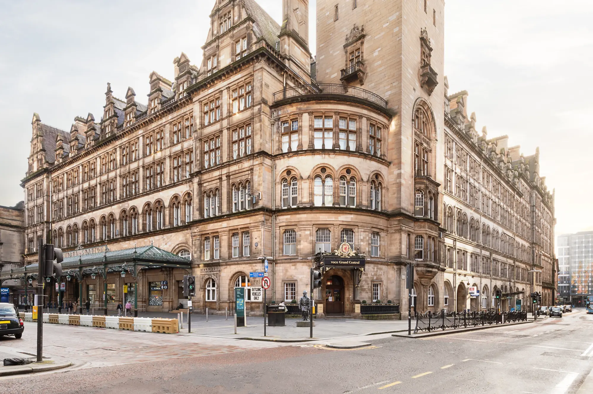 A sparsely populated street visible through light miss, with the historic structure of voco Grand Central Glasgow, an IHG Hotel featuring prominently