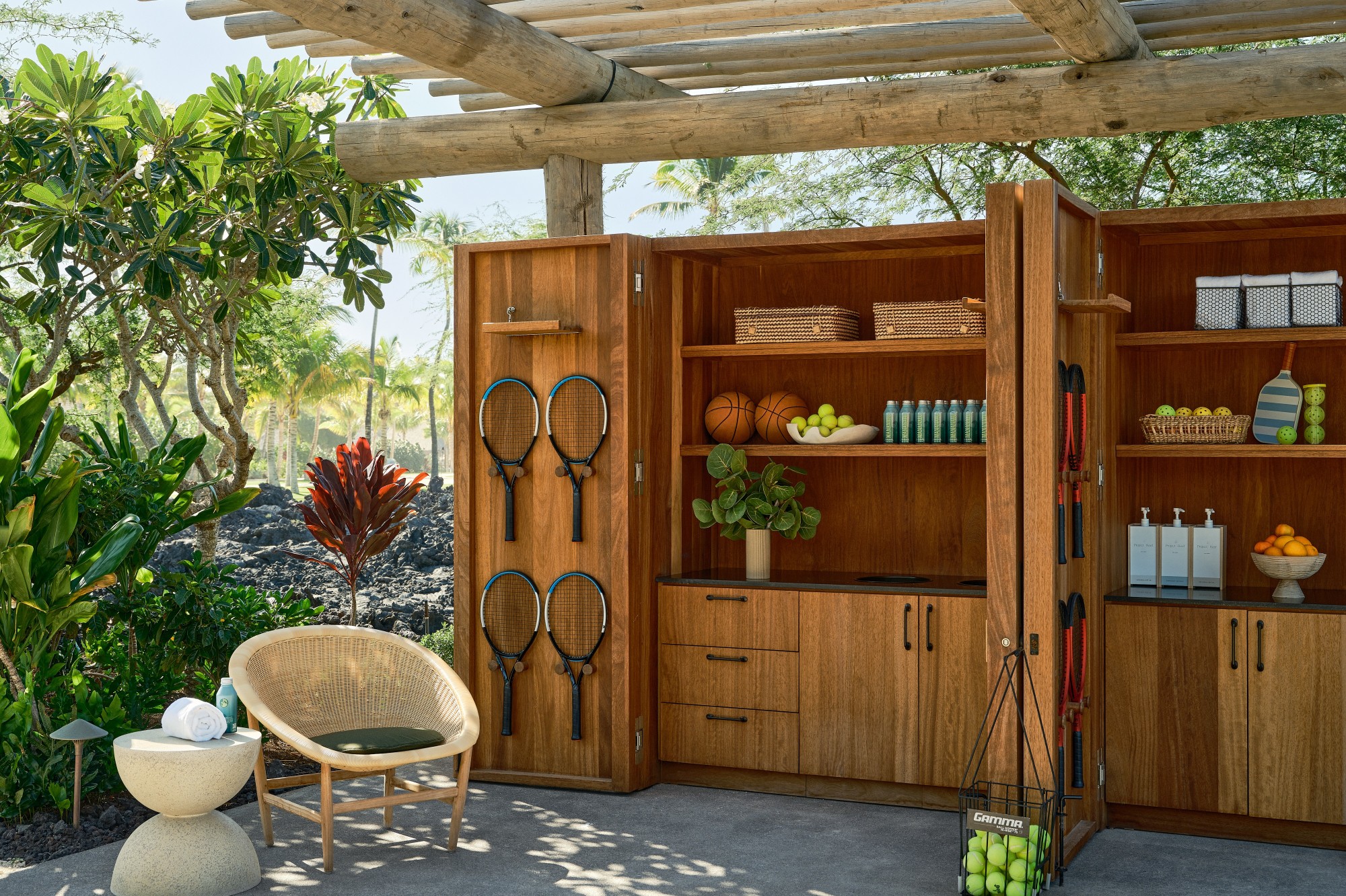 an outdoor break area with seats and shelving containing tennis racquets and balls