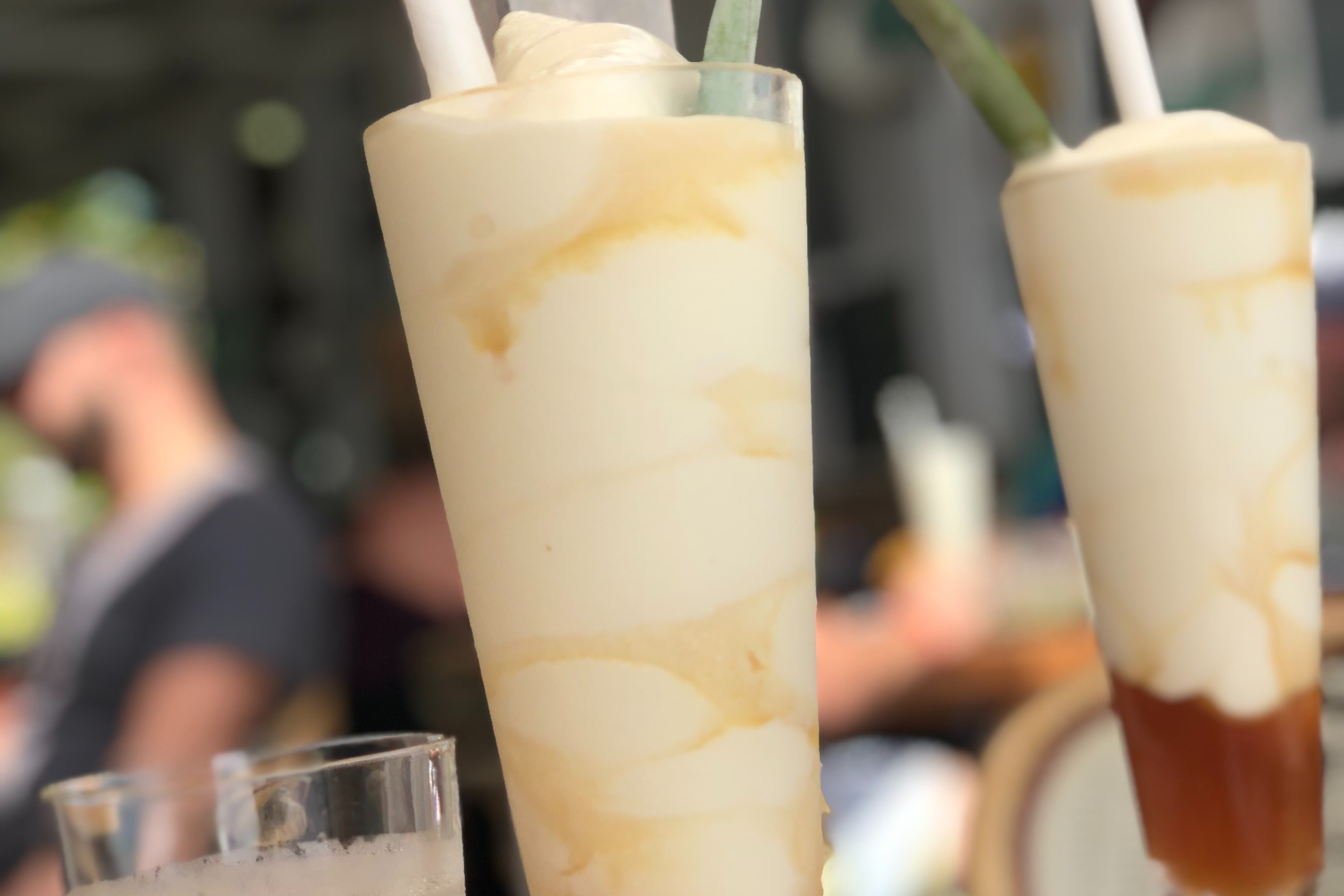 Cocoloba's Pina Coladas sit on a patio table as condensation gathers at their bases on a sunny day.
