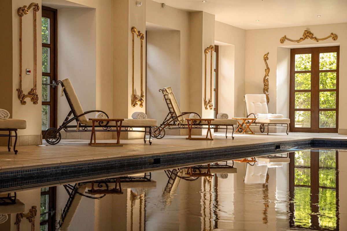 An indoor pool area with three lounge chairs next to the pool