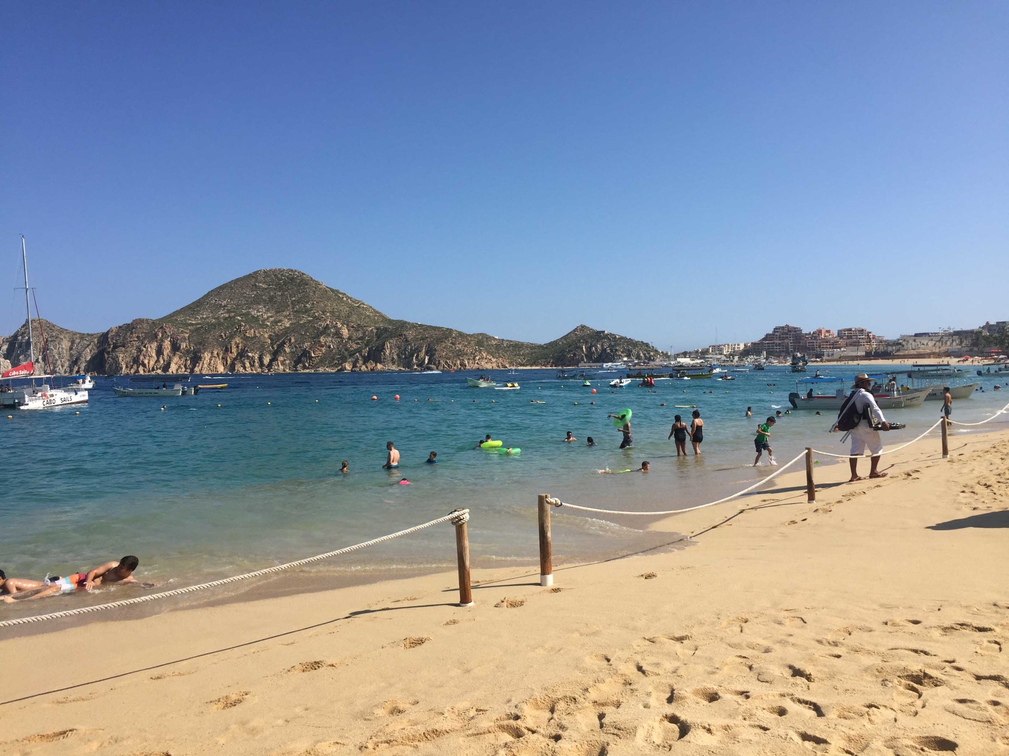 A beach area with mountains in the distance and people playing in the water