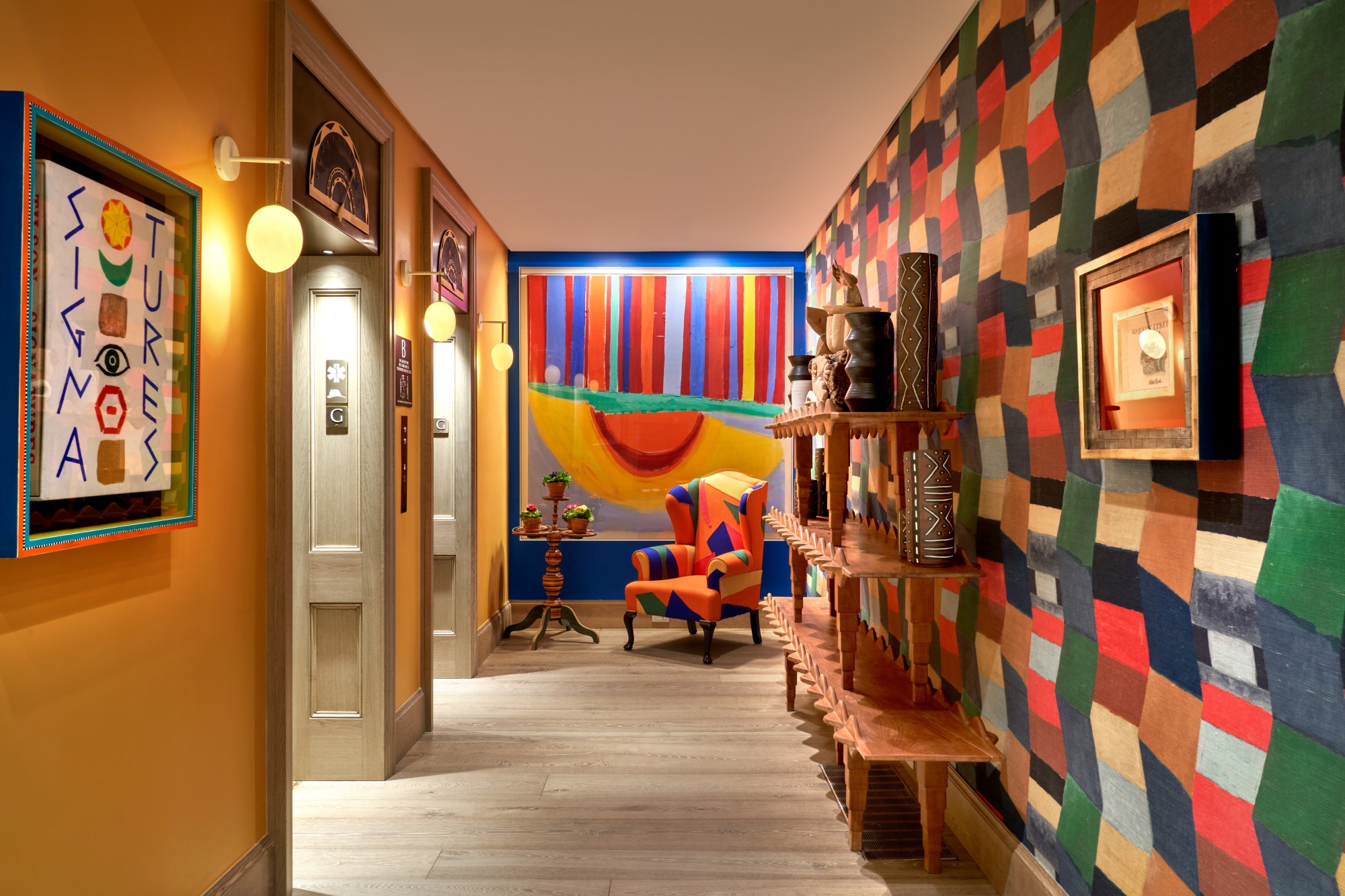 a colorful hall way with a vibrantly patterned upholstered armchair, one wall covered with checkered wallpaper, and the other painted a lovely yellow