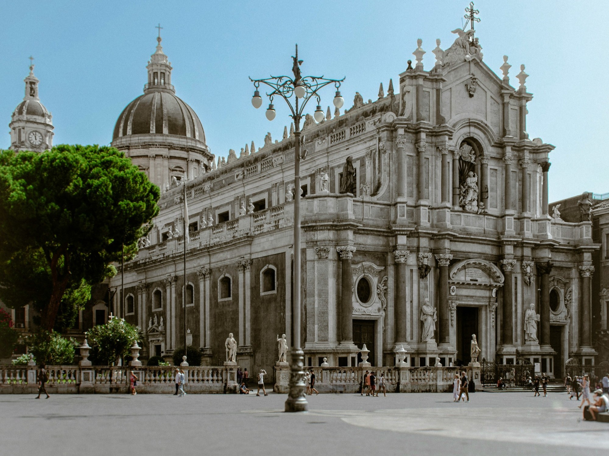 A large stone white cathedral with ornate sculptures and large dome towers during the day.