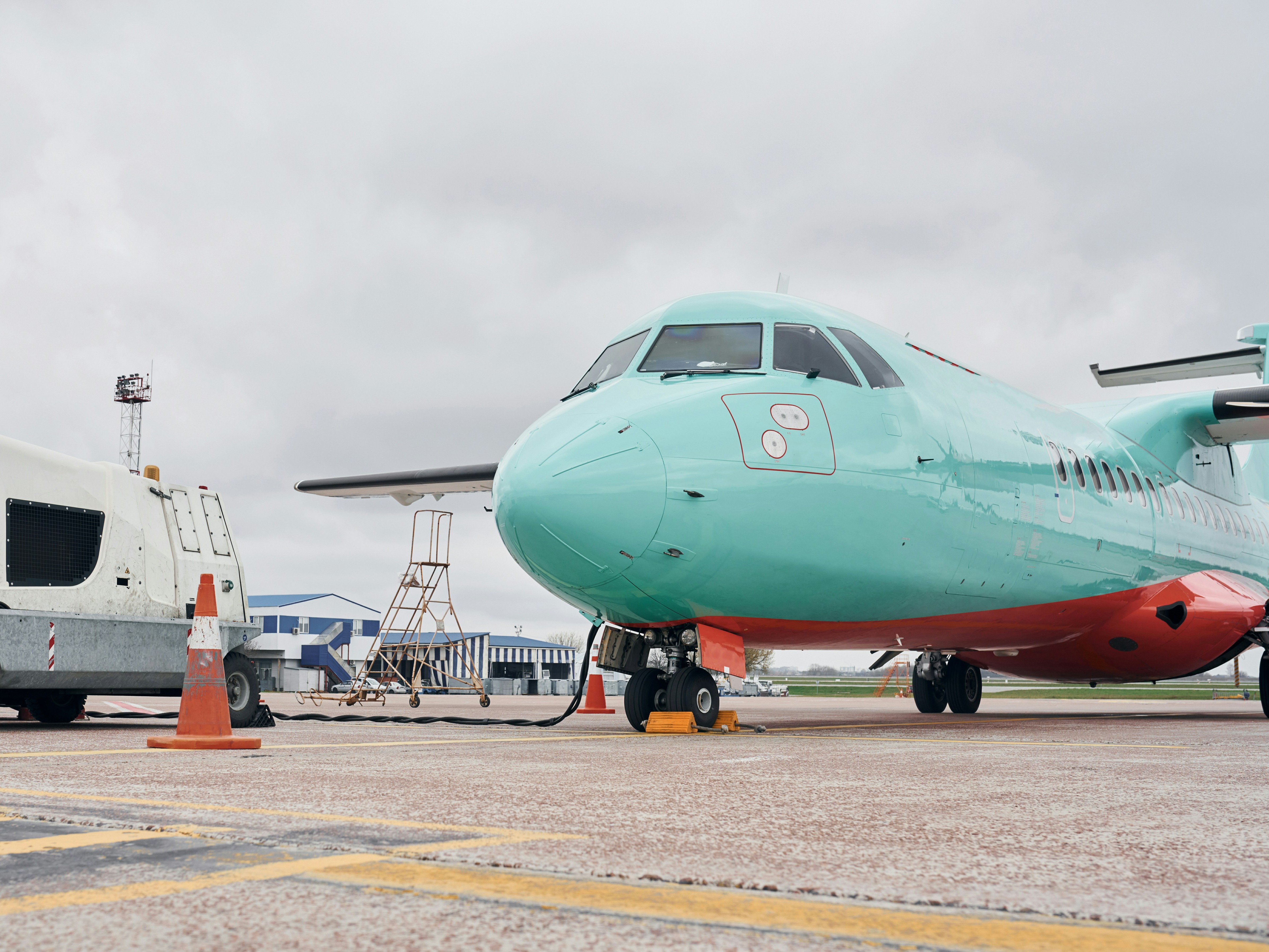 The image shows a close-up view of an aircraft on the tarmac with ground support equipment nearby.