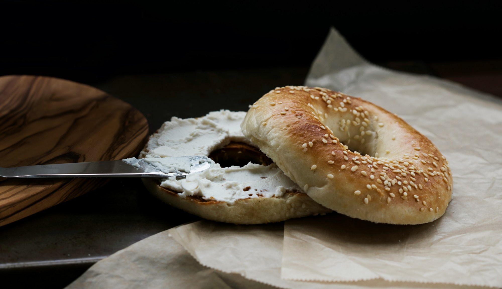 Bagel with cream cheese on a piece of wax paper.