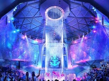 A captivating indoor waterfall bathes in a symphony of blue and purple lights.