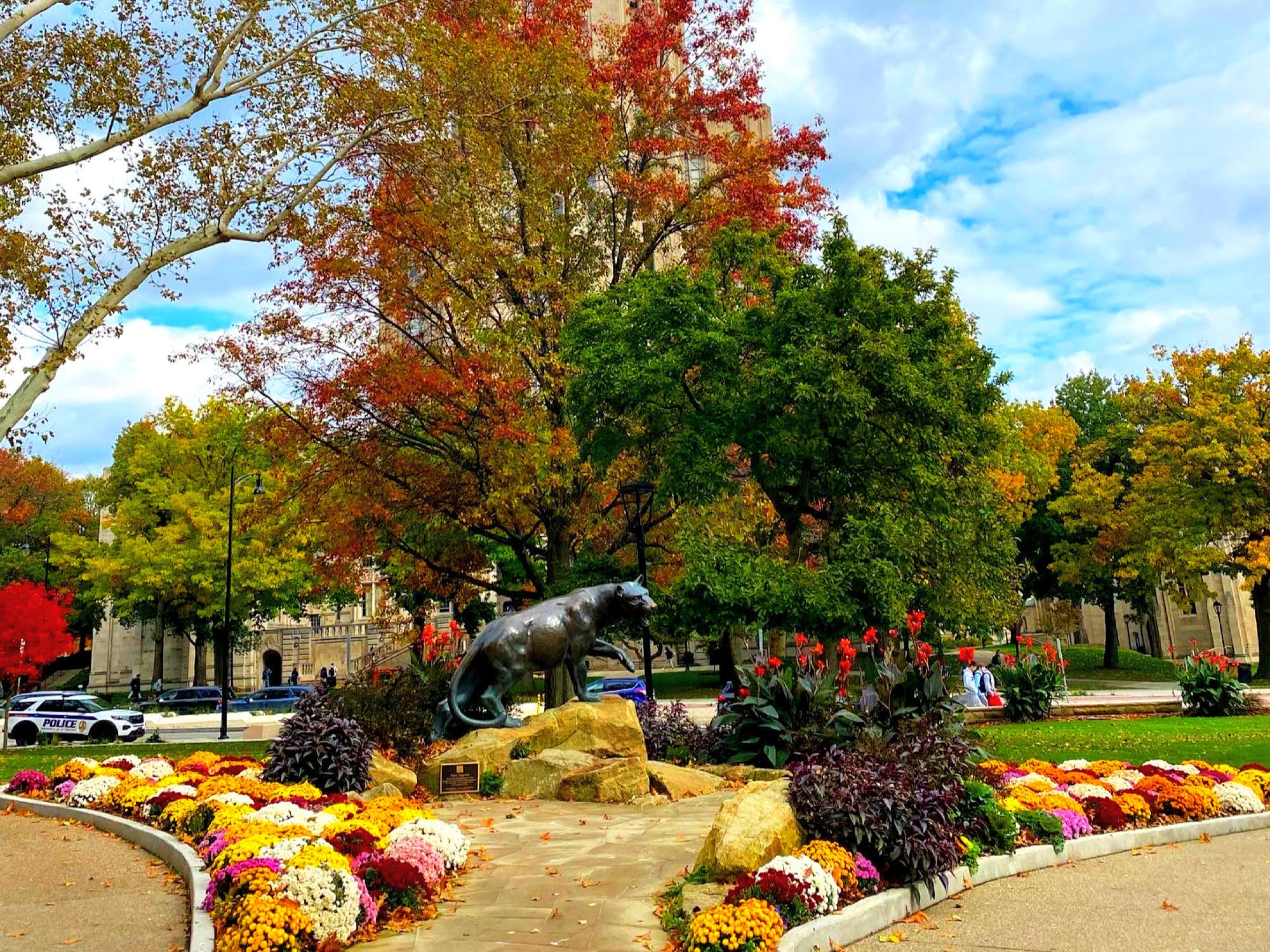 Colorful flowers and trees in front of a building.