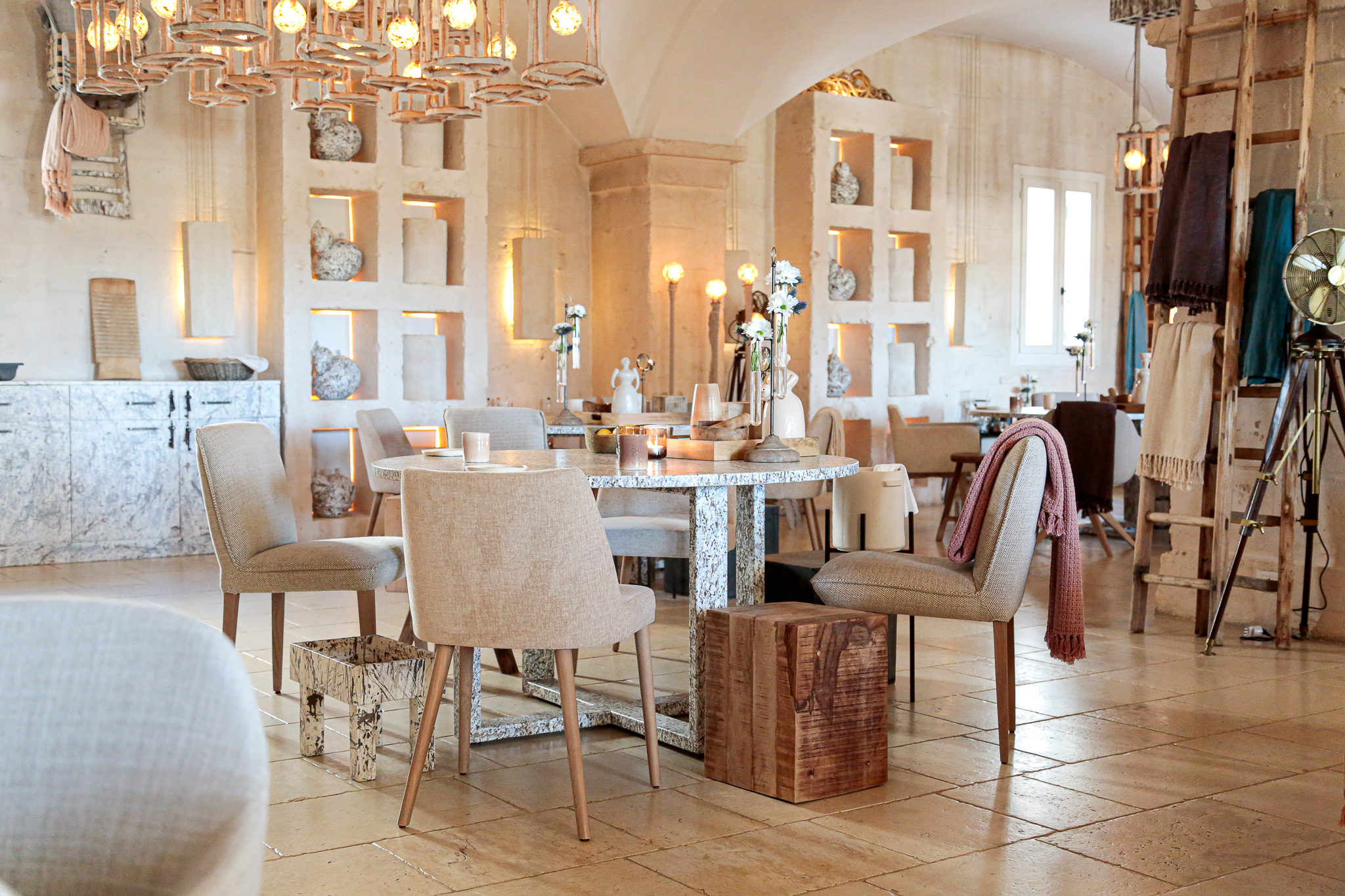 A spacious dining room with white walls and light wood floors, four chairs surround a table at Due Camini in Borgo Egnazia.