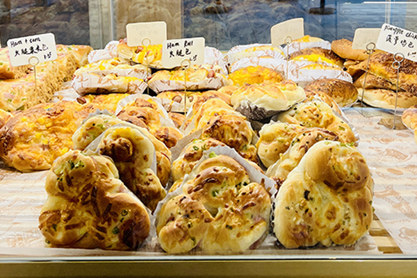 Bakery items on display in a well-lit case lined with parchment.