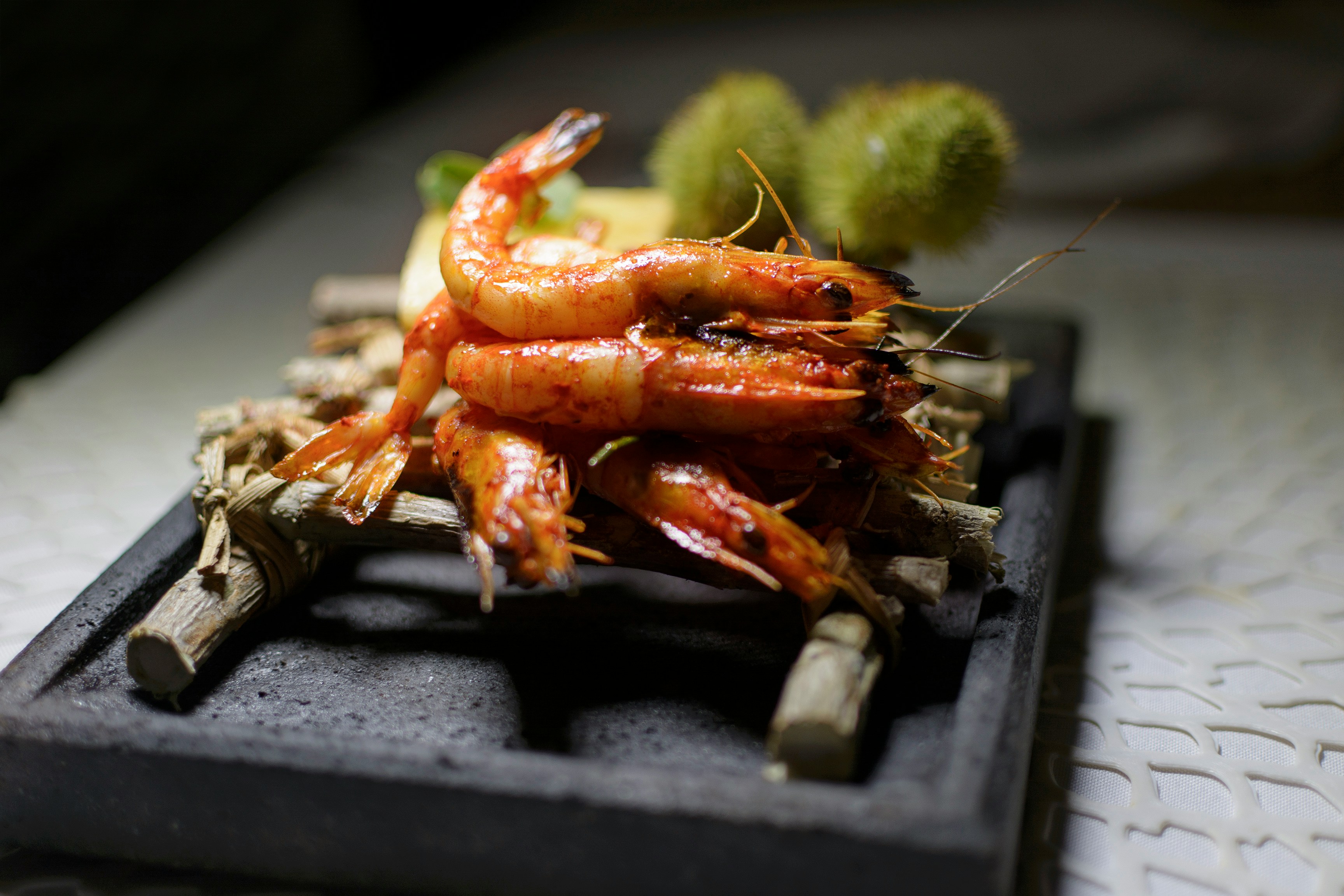 A pile of red prawns on a black dish.