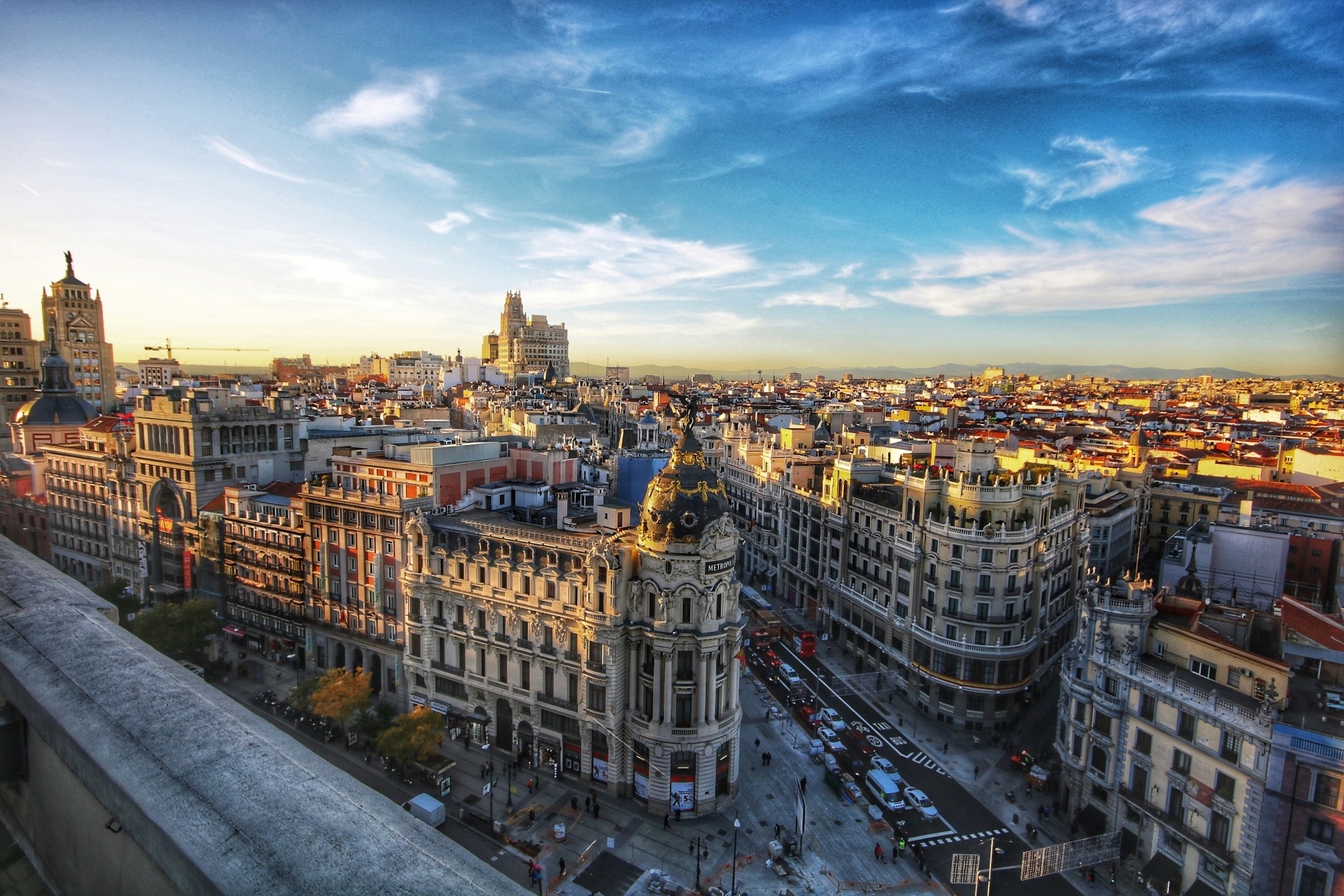 A skyline view of the city as histroic buildings reach toward a clear sky dotted with wispy clouds.