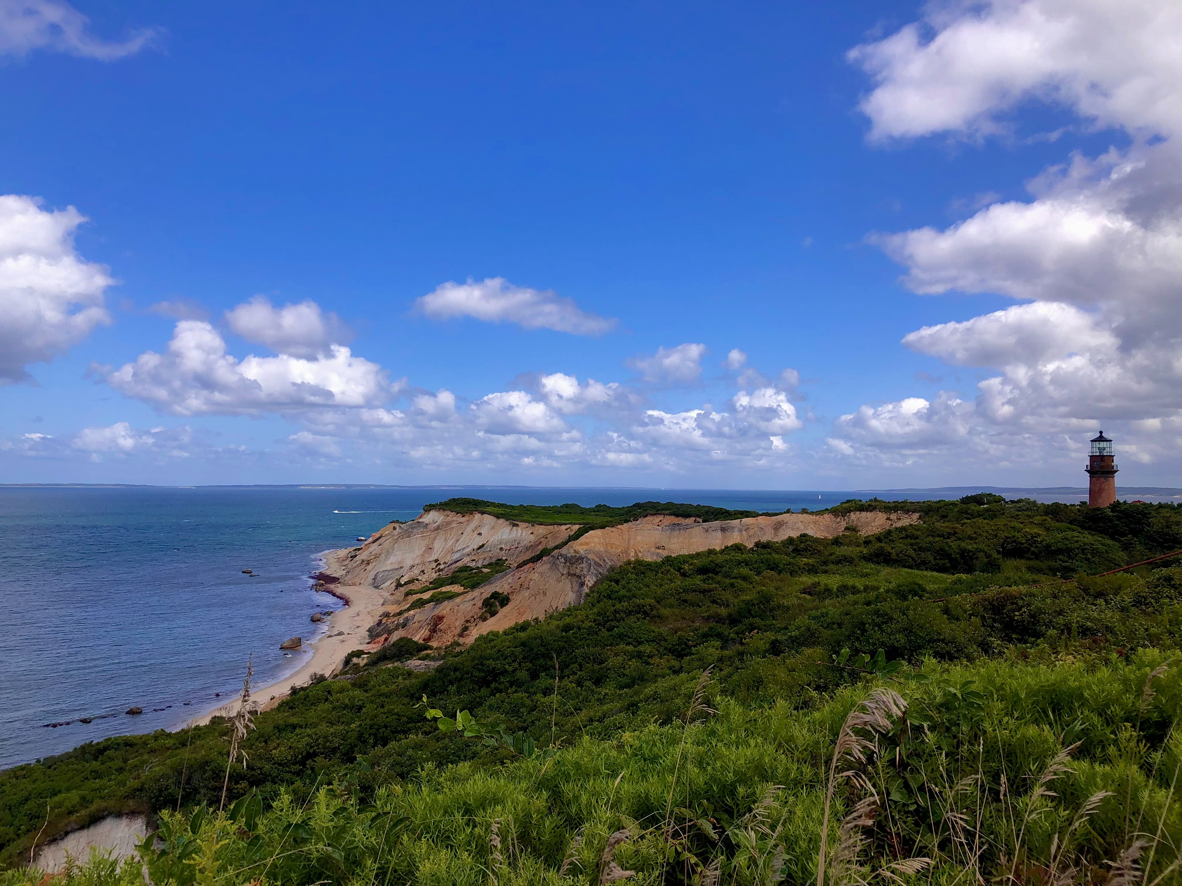 A picturesque coastal scene with a lighthouse perched on a cliff under a serene blue sky.