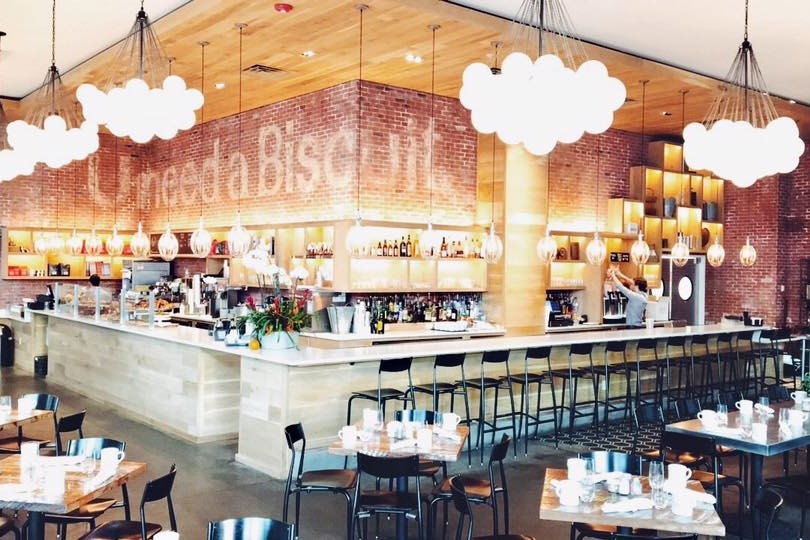 The dining area of Willa Jean, a contemporary bakery, bar, and restaurant with modern amenities in a well-lit space.
