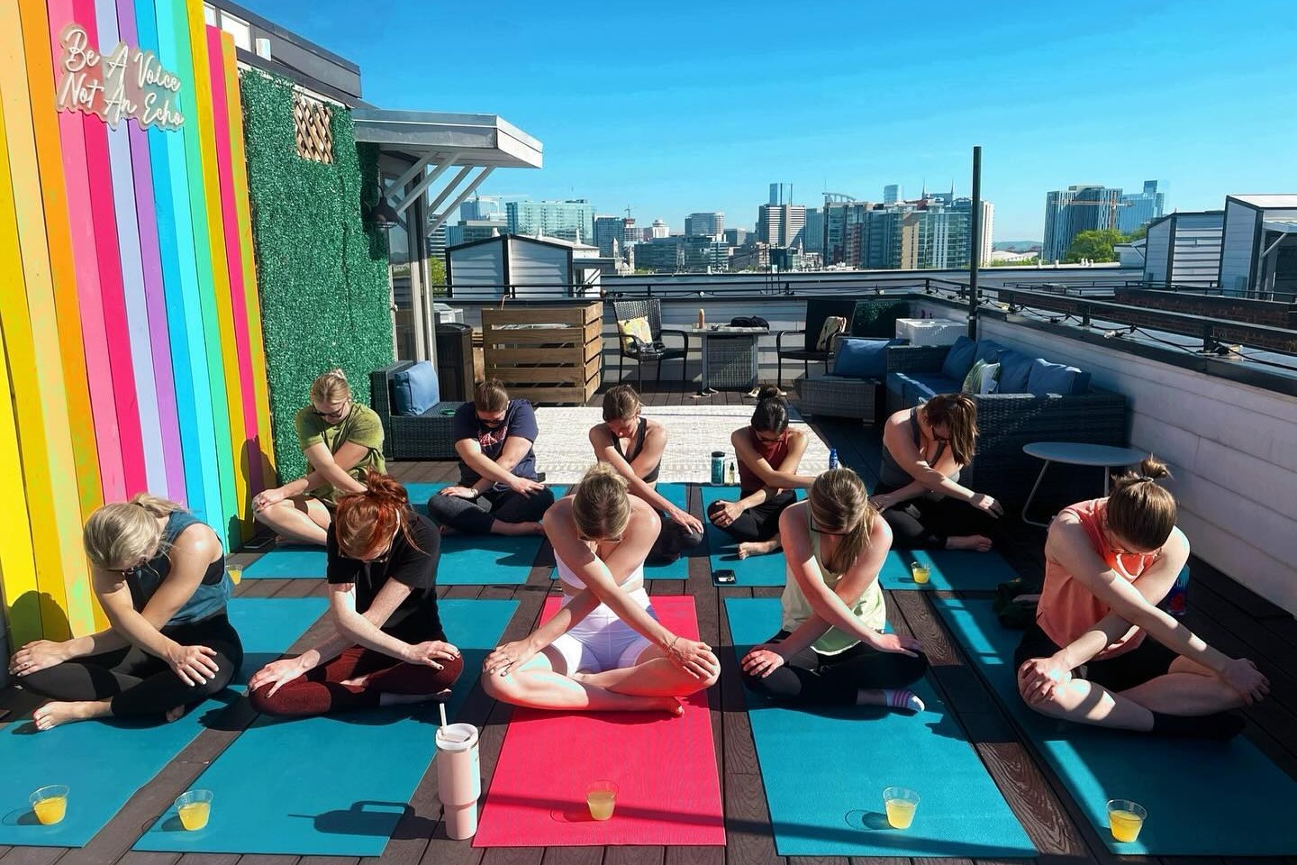 A yoga class strikes a pose on mats on an outdoor patio on a sunny day.