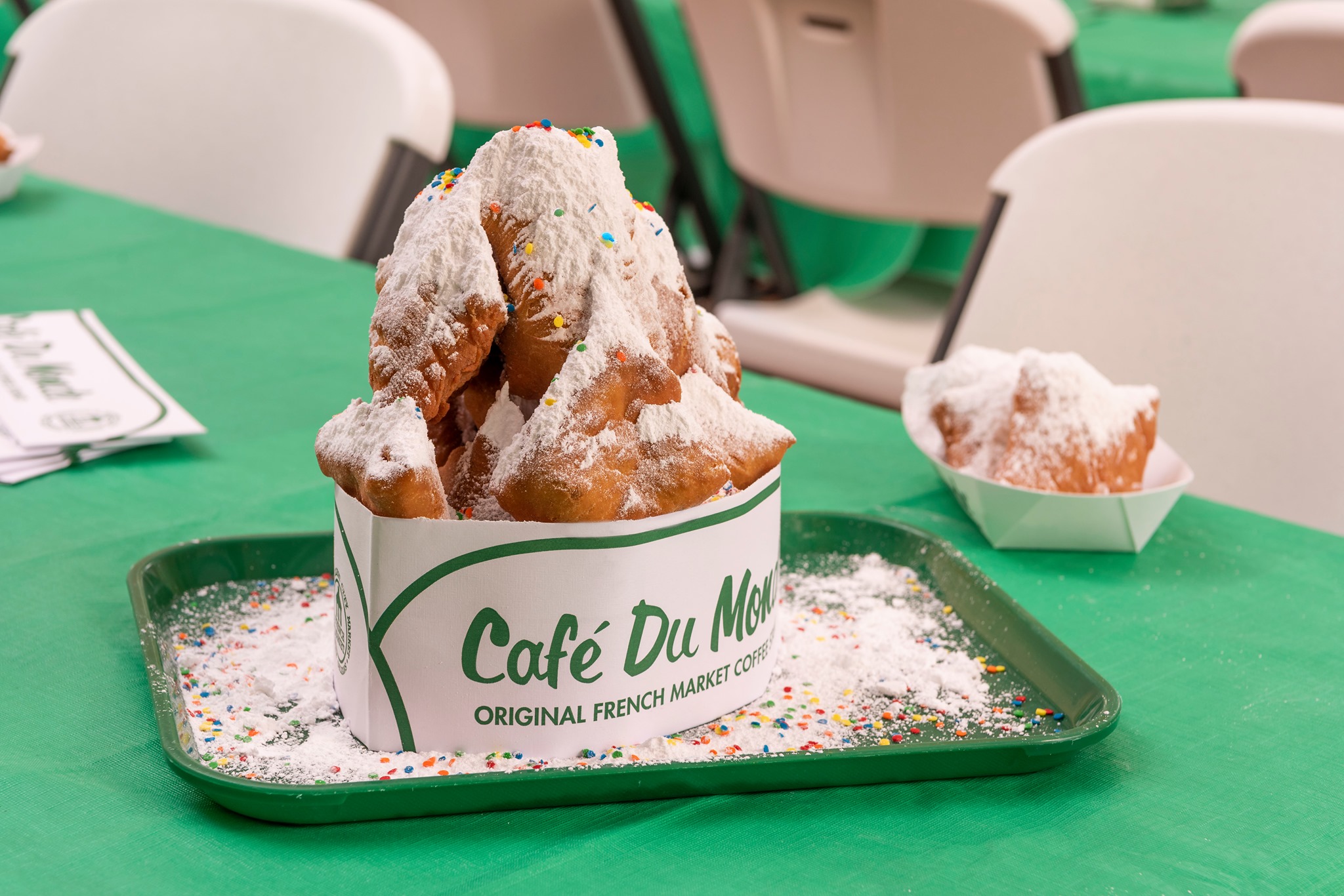Beignets from Cafe du Monde piled high with powdered sugar on a patio tray.