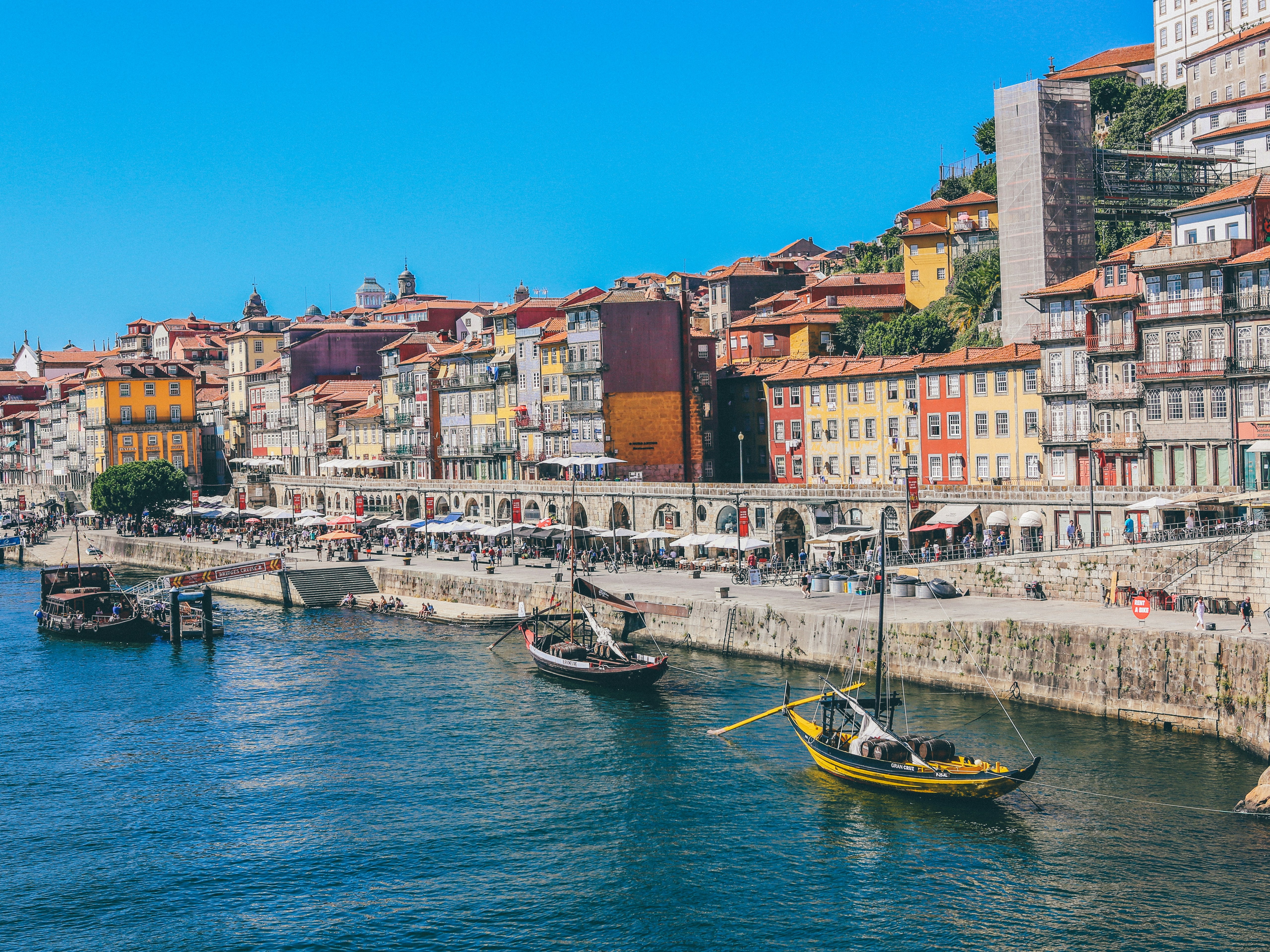 Boats in blue water along a harbor with colorful buildings.